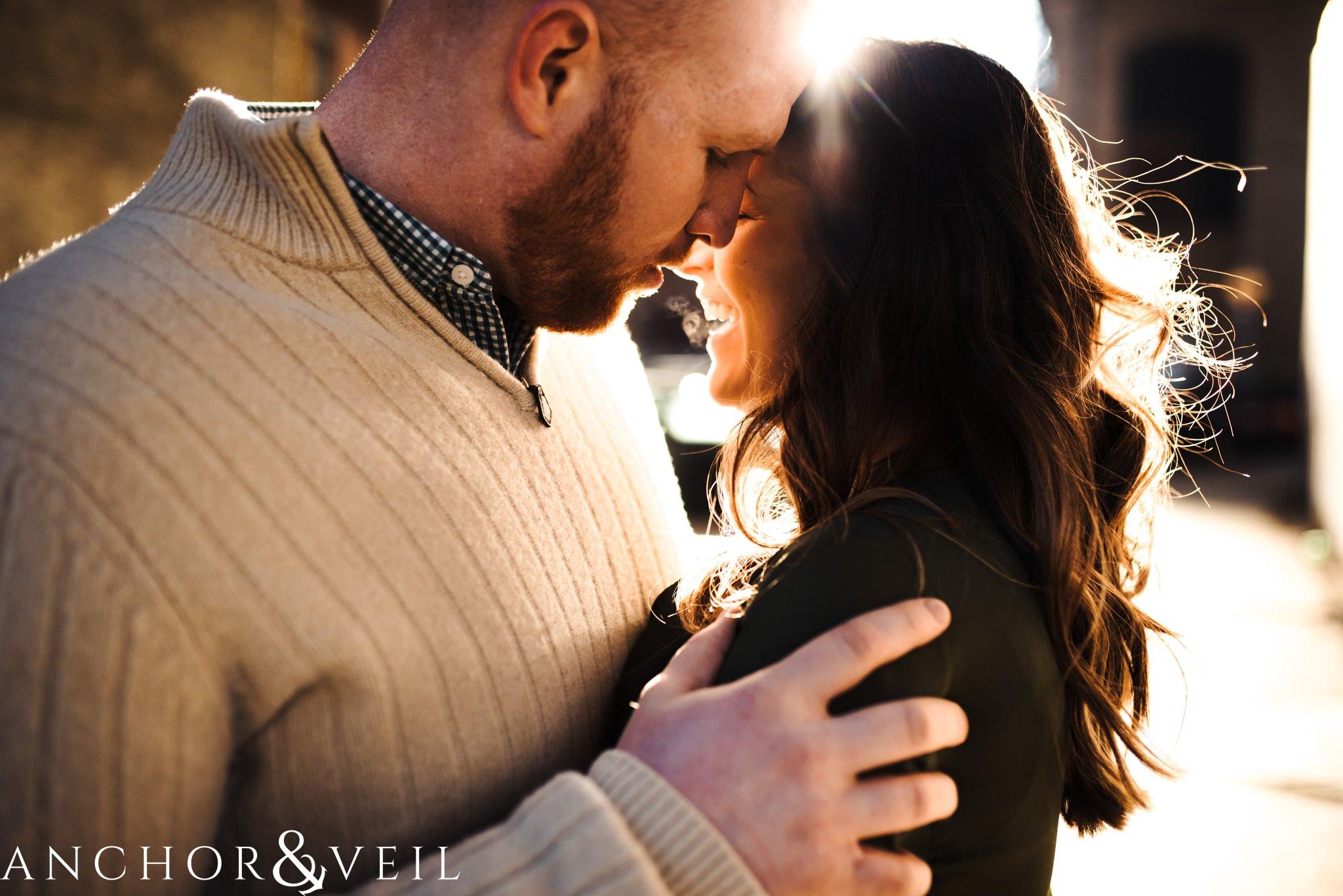 leaning together close in the light During their Dumbo Brooklyn New York engagement session