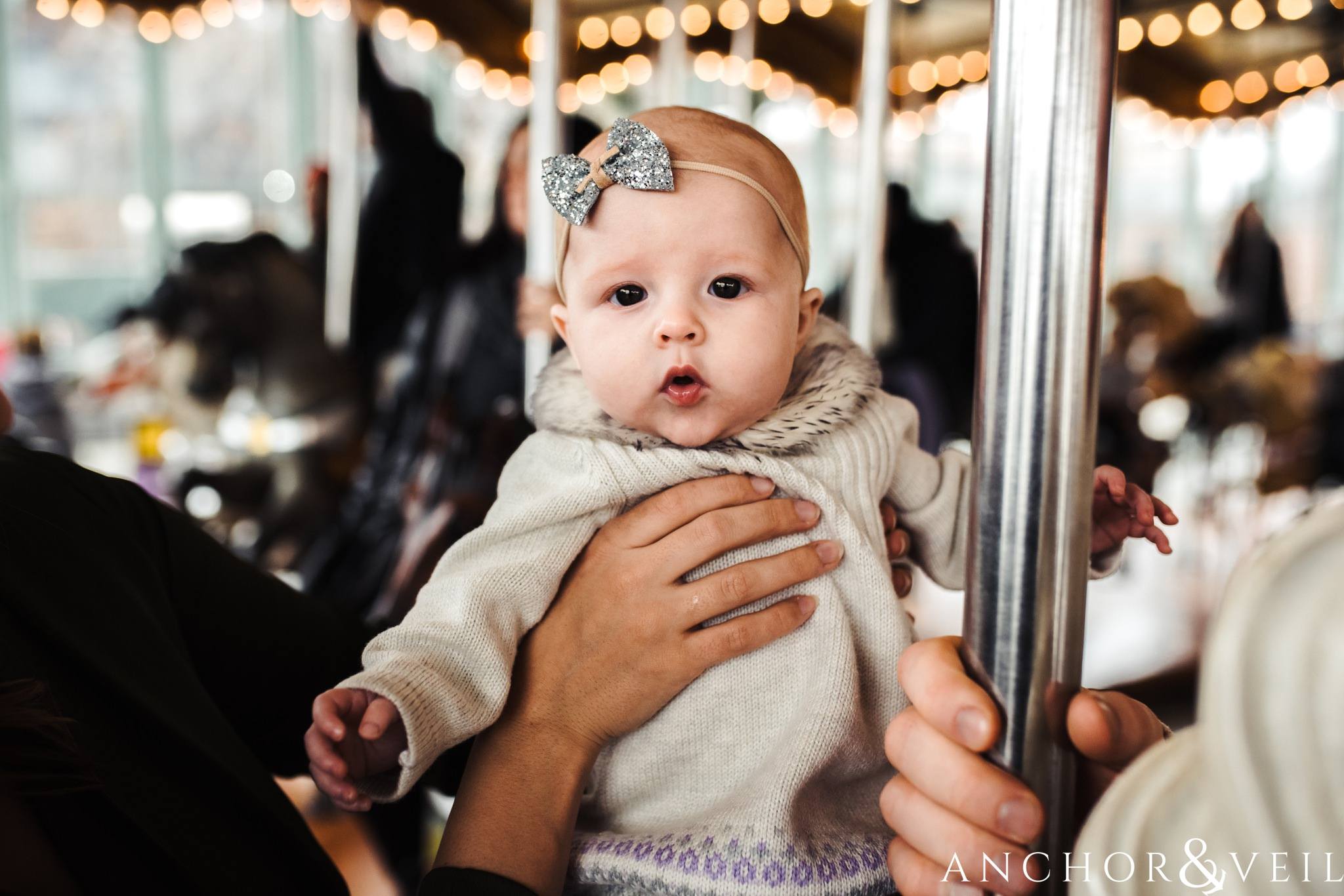 Holding the baby in the carousal During their Dumbo Brooklyn New York engagement session