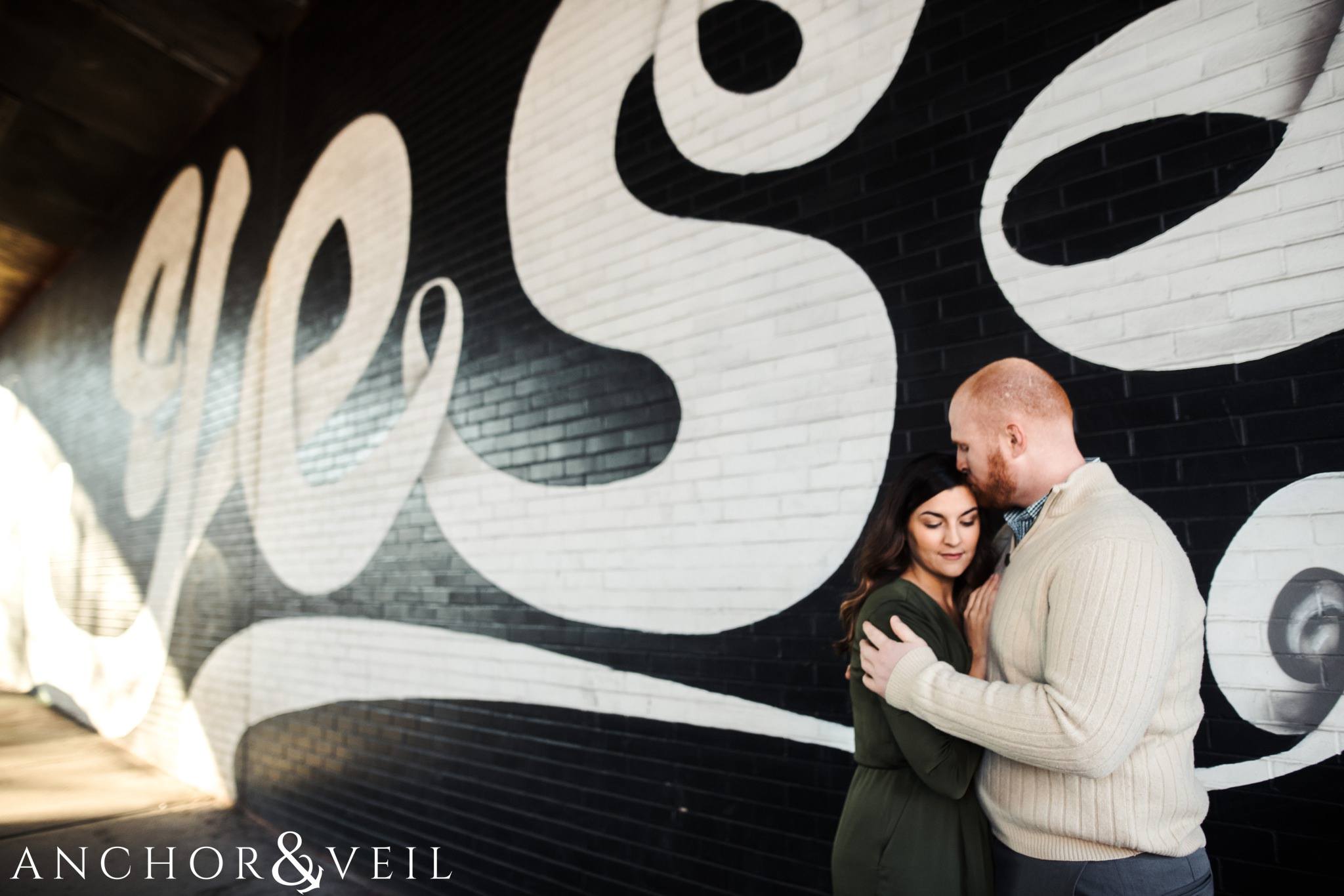 hugging in front of the yes mural During their Dumbo Brooklyn New York engagement session