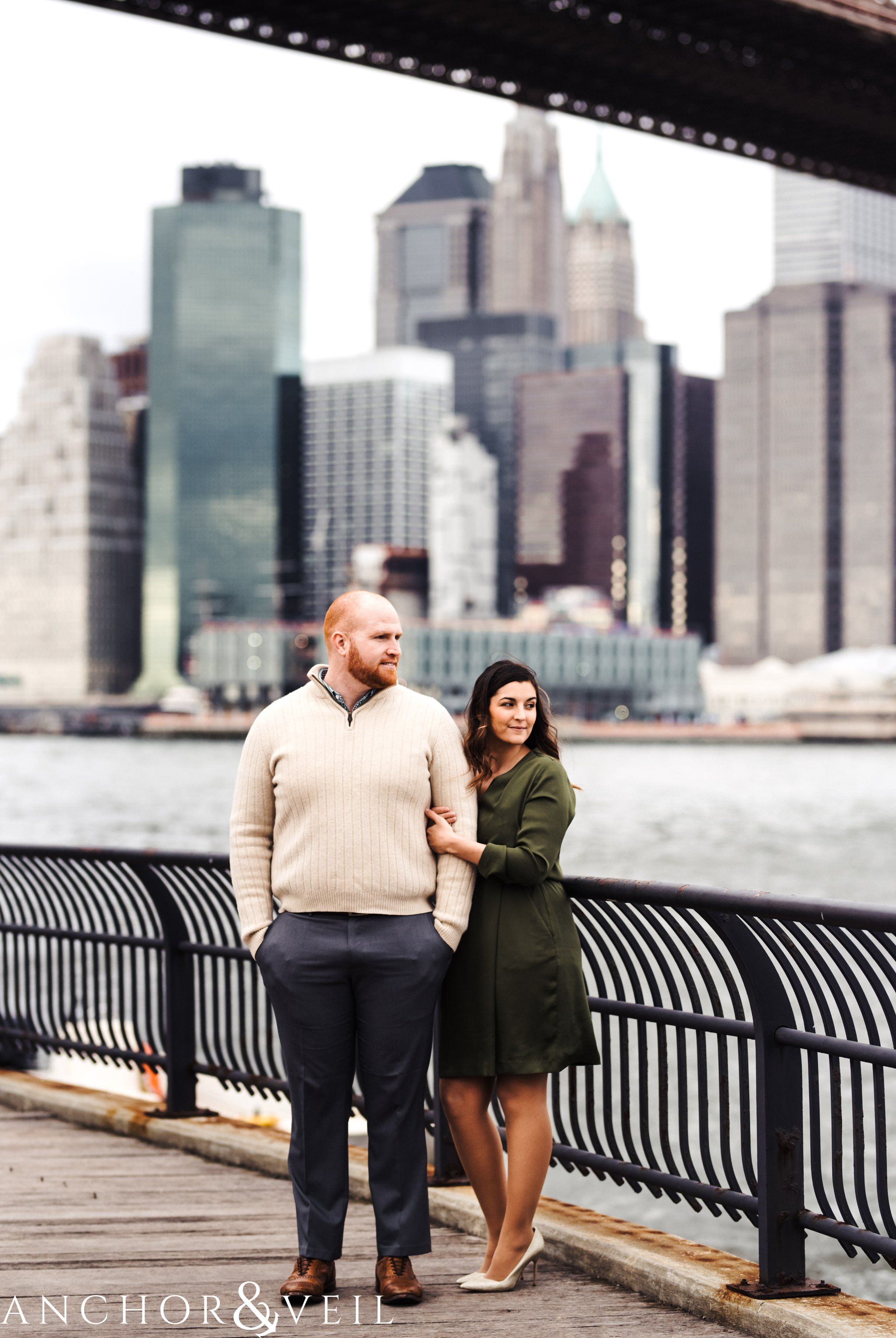 holding each other overlooking Manhattan During their Dumbo Brooklyn New York engagement session
