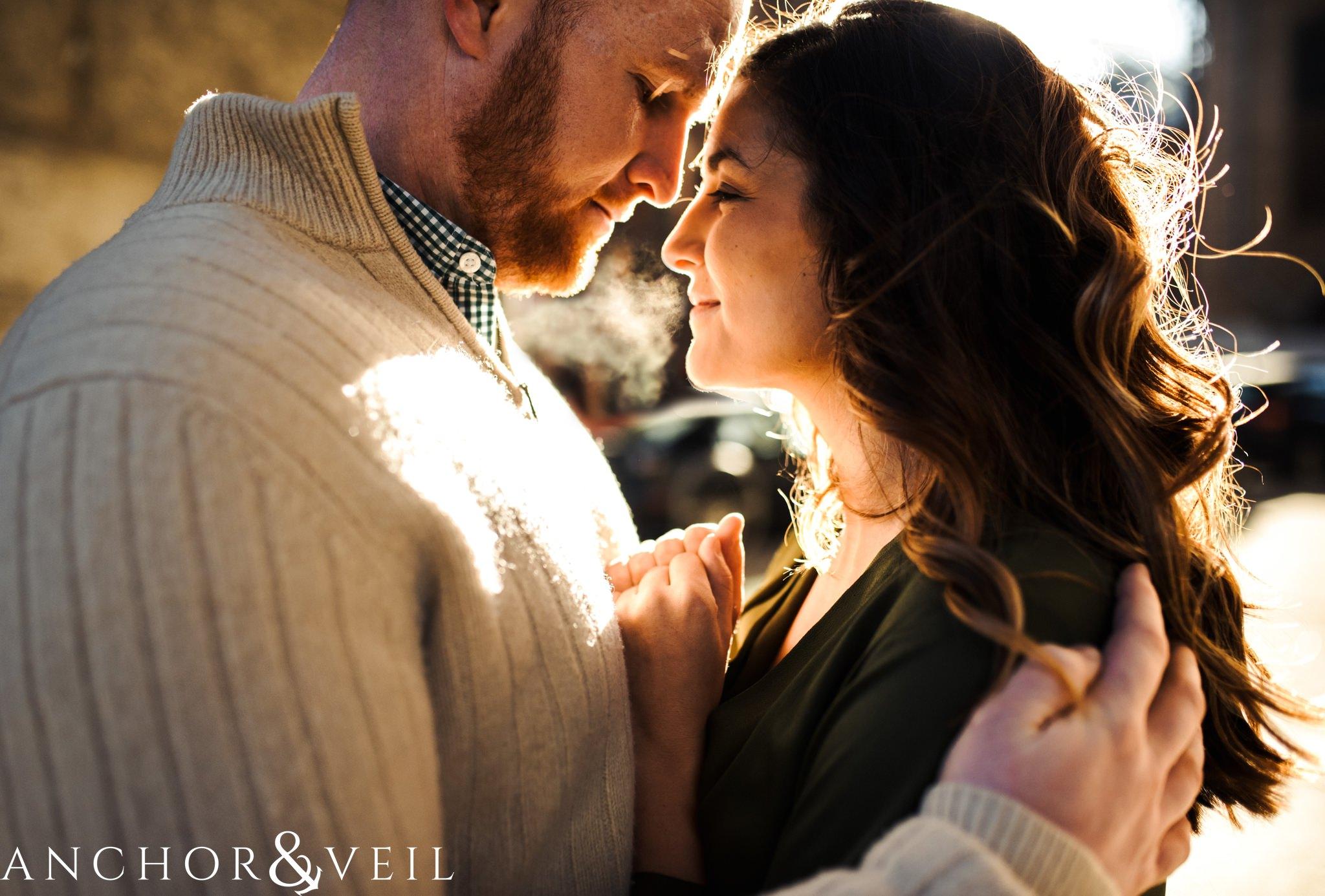 steam from the cold as they hug each other During their Dumbo Brooklyn New York engagement session