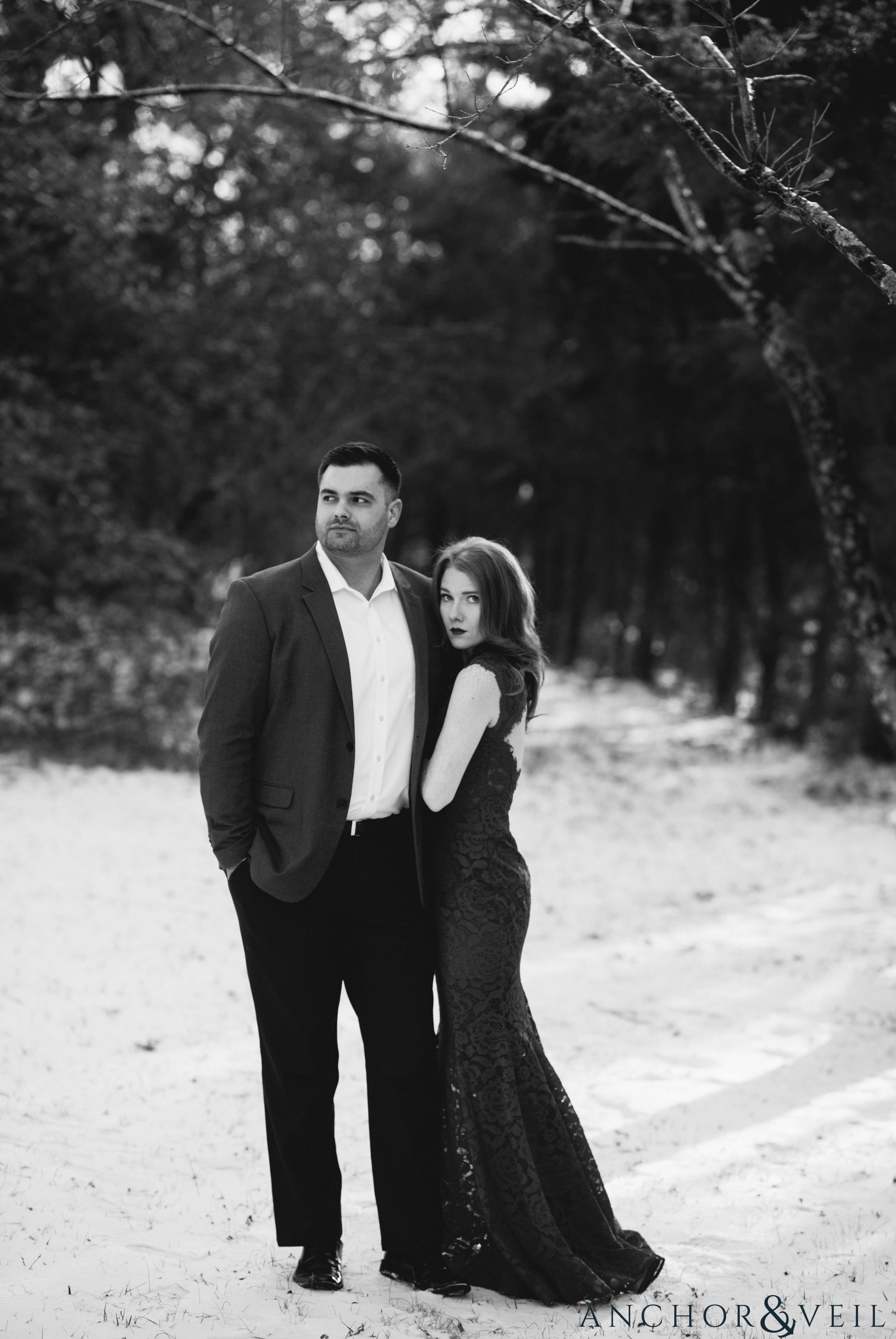 looking off in teh distance during their Charlotte Snow engagement session in the woods