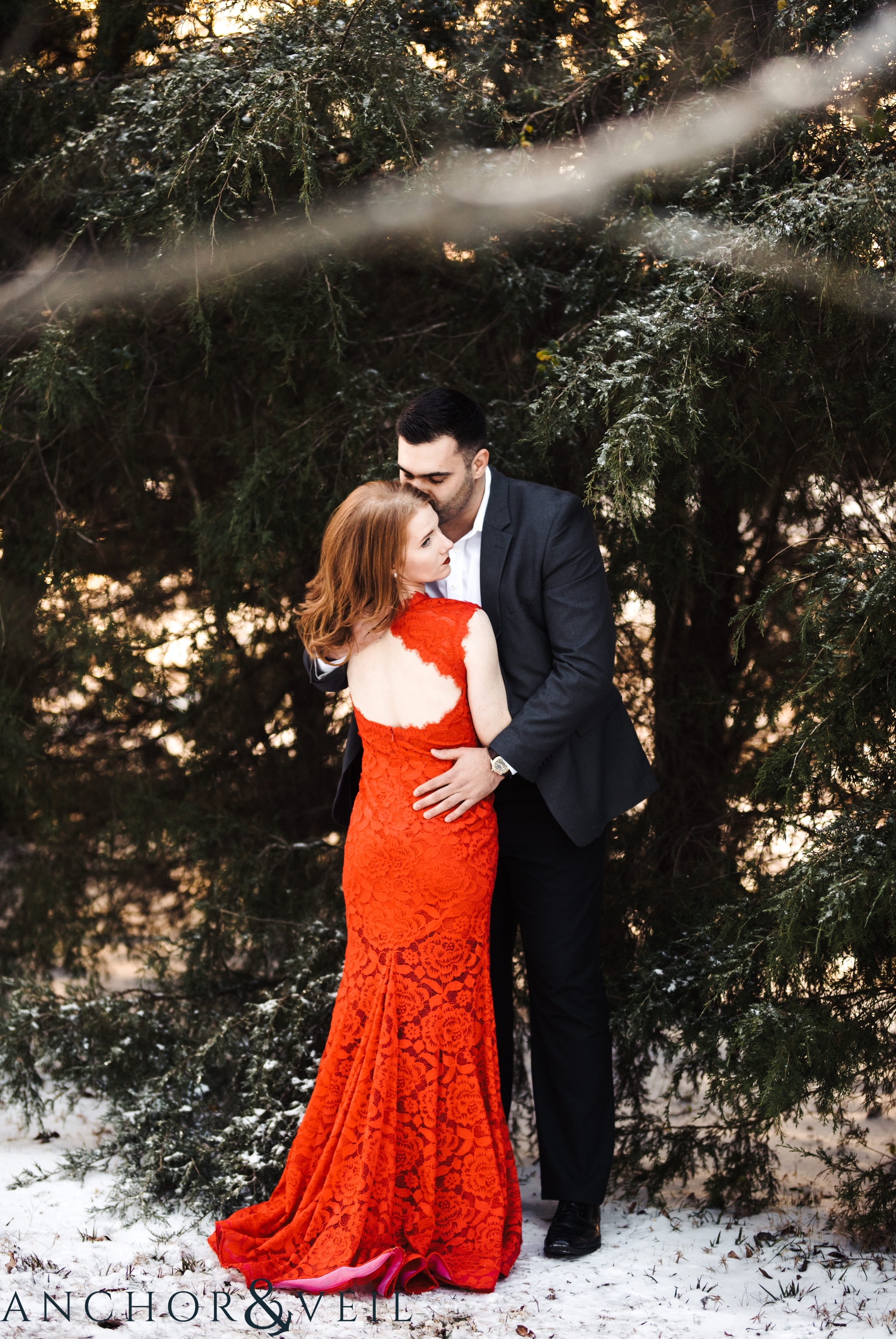 the beautiful red dress during their Charlotte Snow engagement session in the woods