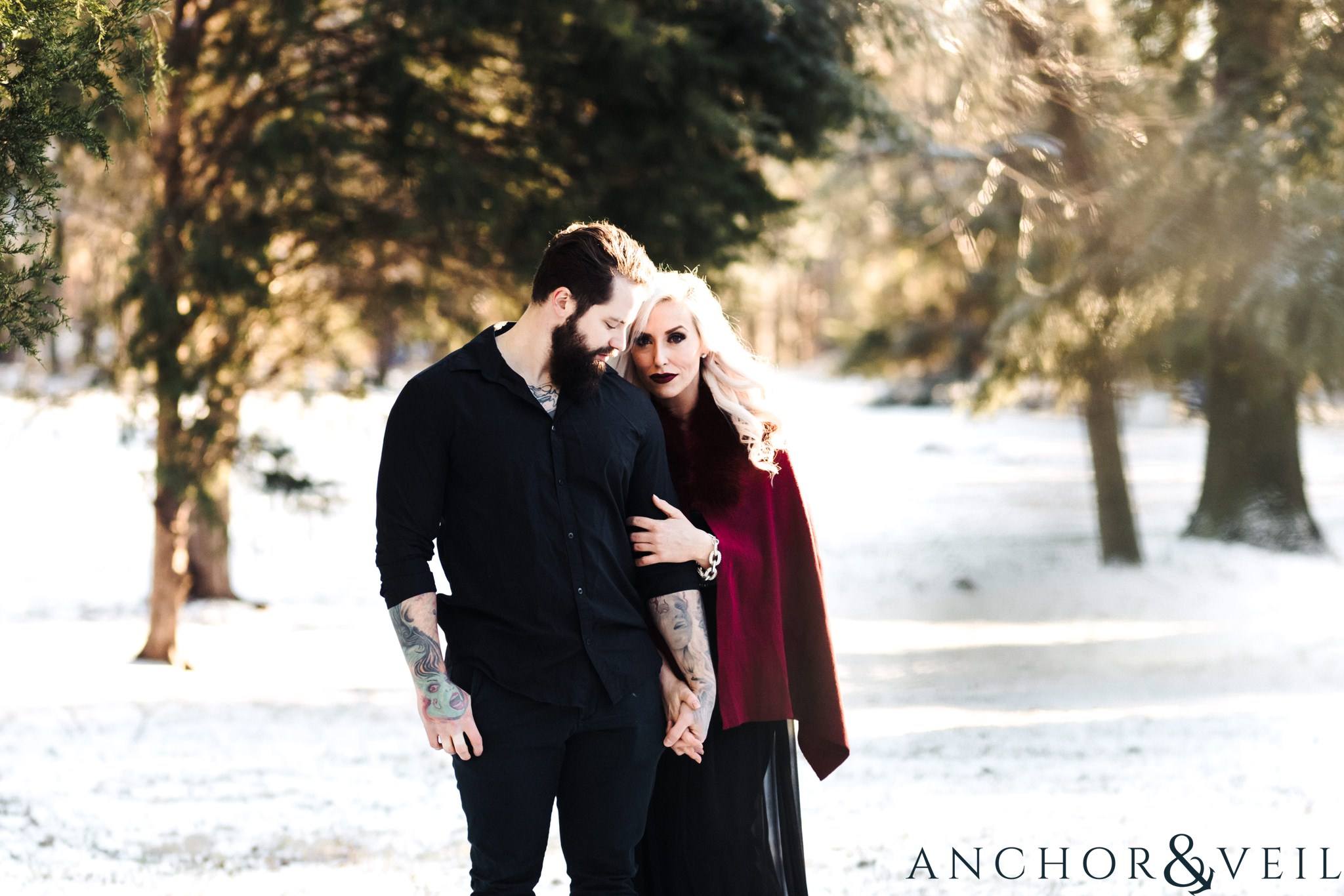 standing in the snow holding each other during their charlotte snow engagement session