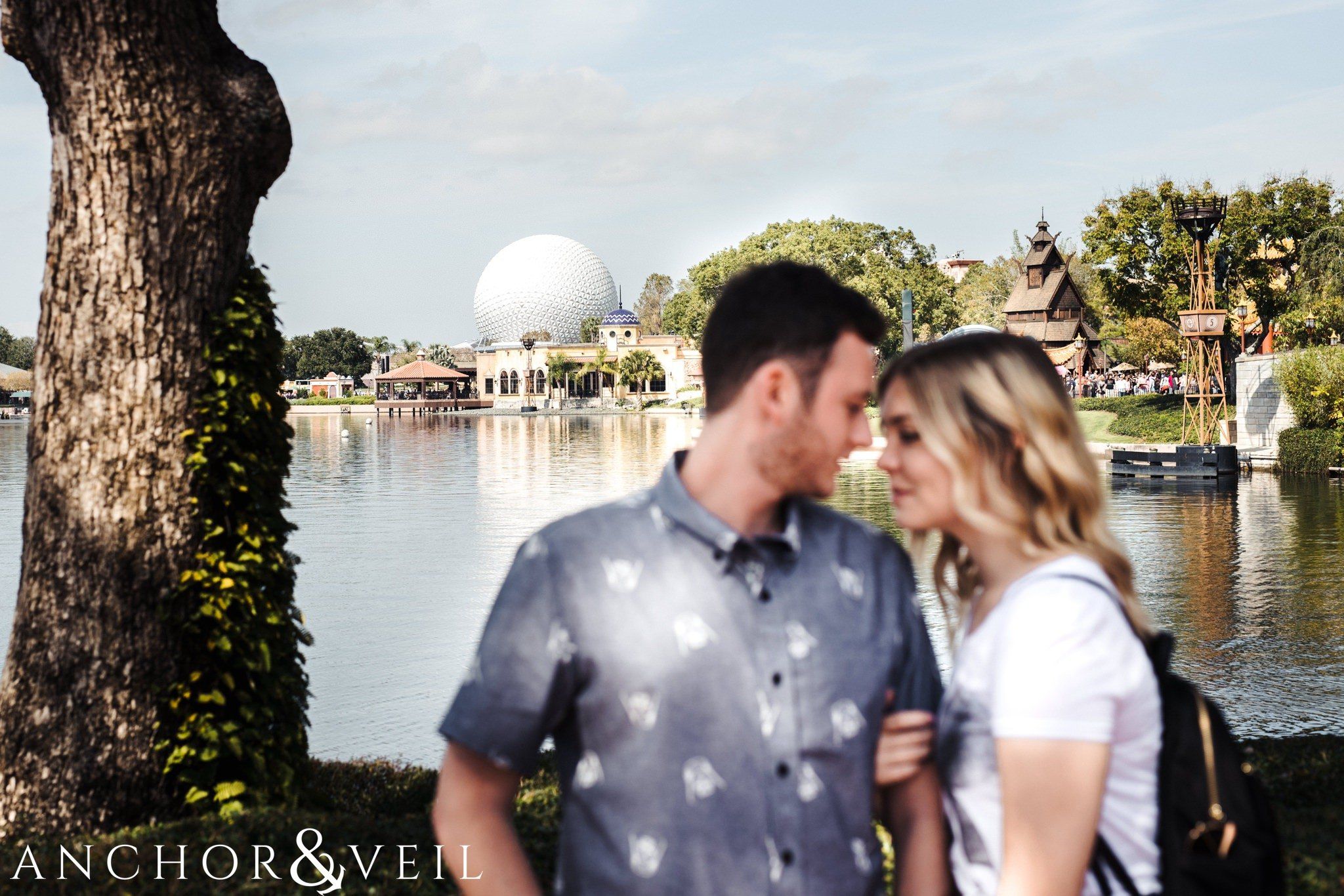 epcot ball in the background during their Disney world engagement session at Disney's Epcot