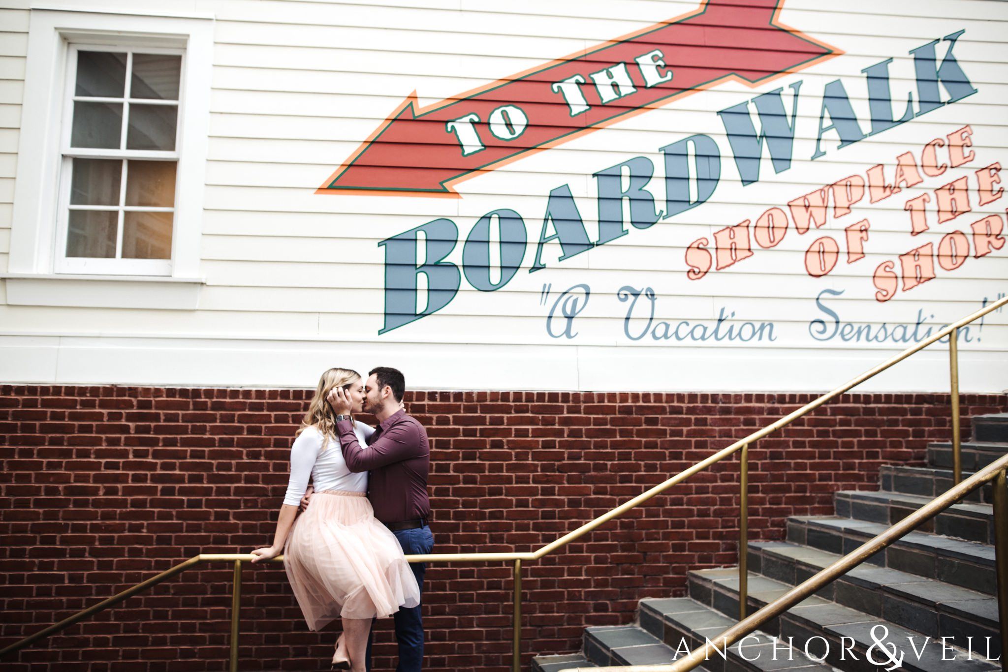 sitting on the boardwalk rails during their Disney world engagement session at the Boardwalk Hotel Inn