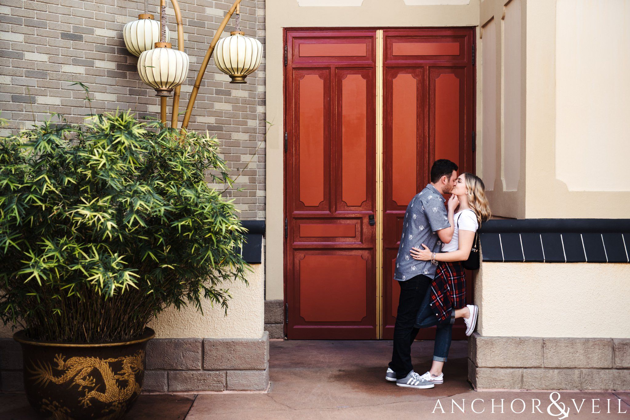 kissing in front of the door in china during their Disney world engagement session at Disney's Epcot