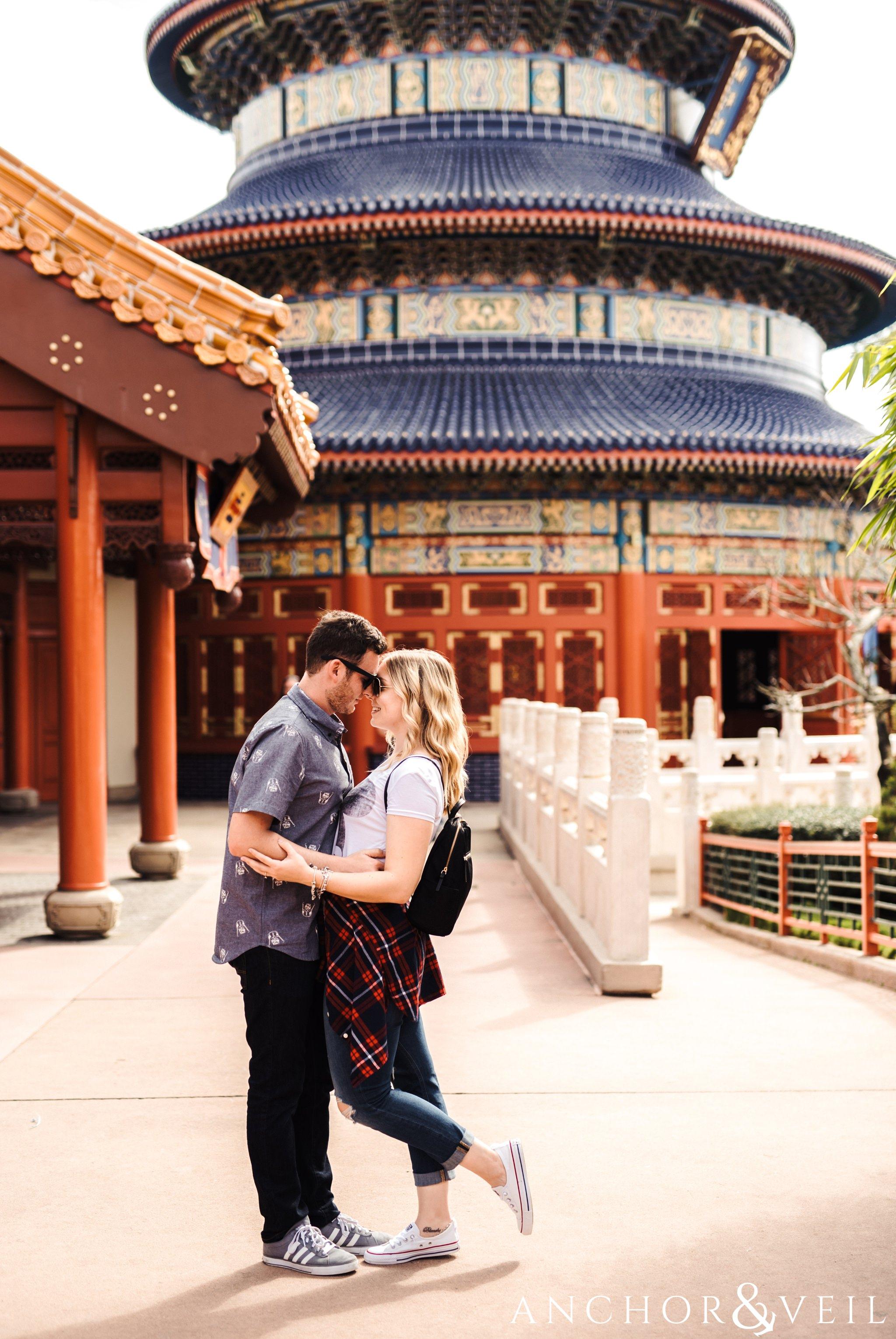 in front of the temple in china during their Disney world engagement session at Disney's Epcot