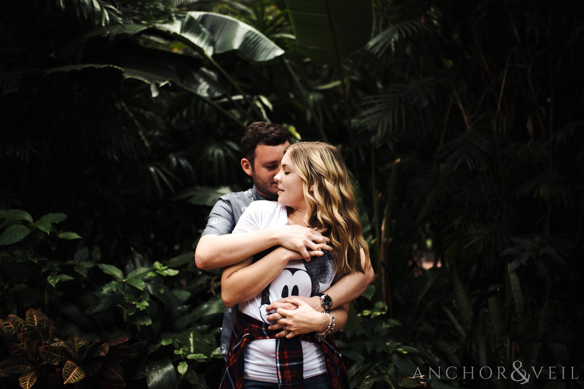 holding her in the jungle of Mexico during their Disney world engagement session at Disney's Epcot
