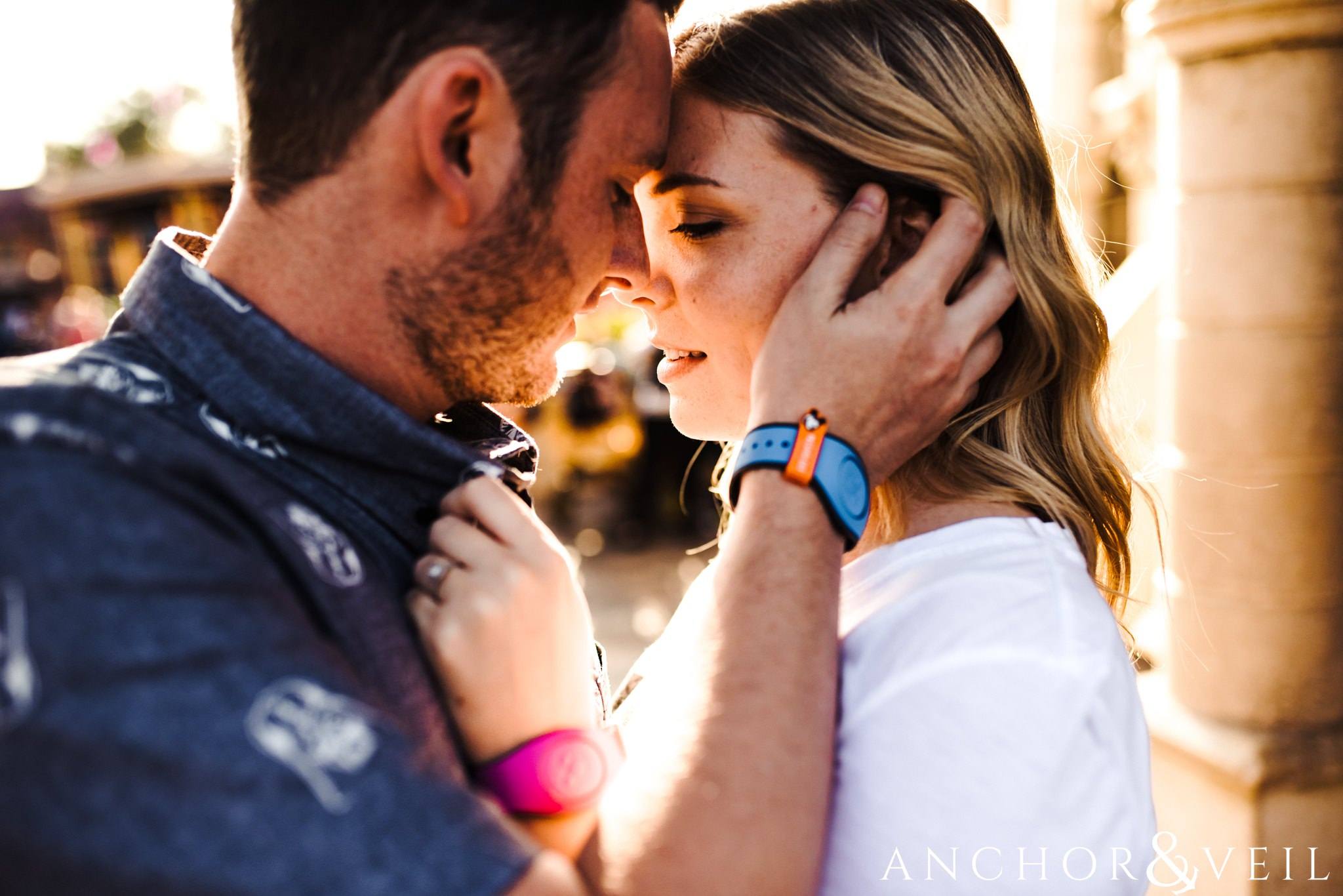 pulling her face close during their Disney world engagement session at Disney's Magic Kingdom