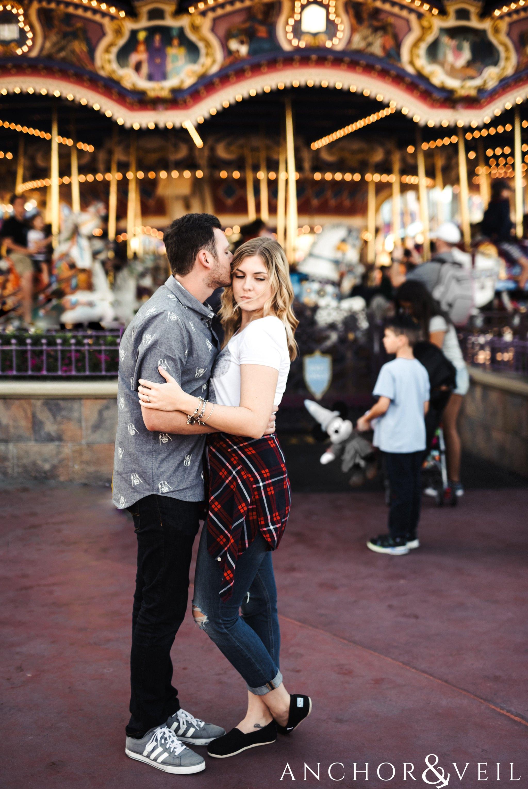 in front of the carousel during their Disney world engagement session at Disney's Magic Kingdom