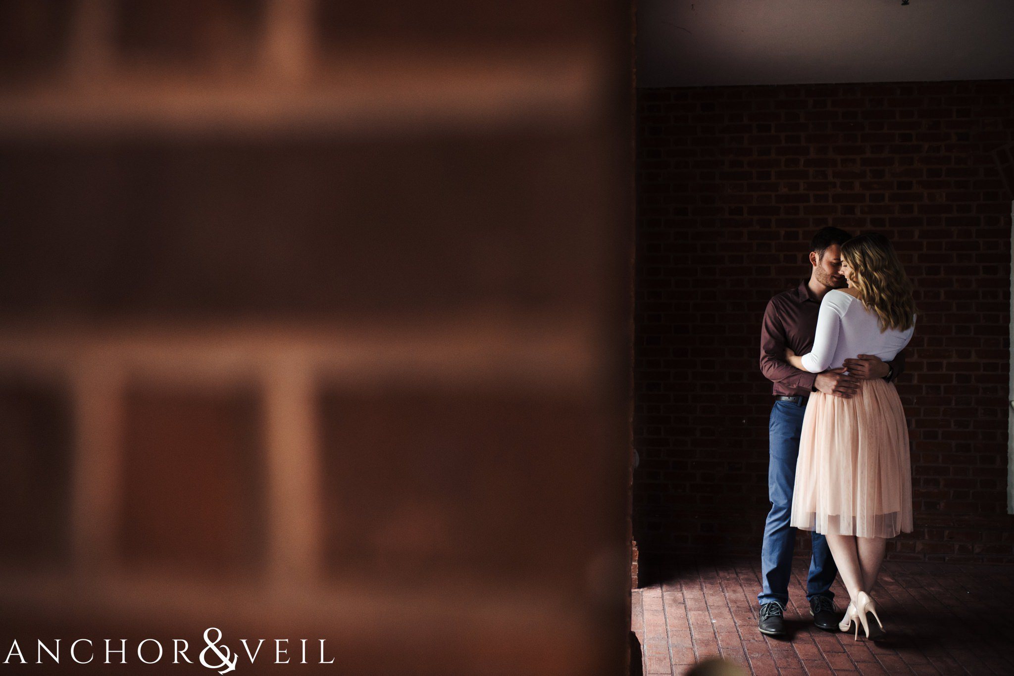 in the shadows next to the brick wall during their Disney world engagement session at the Boardwalk Hotel Inn
