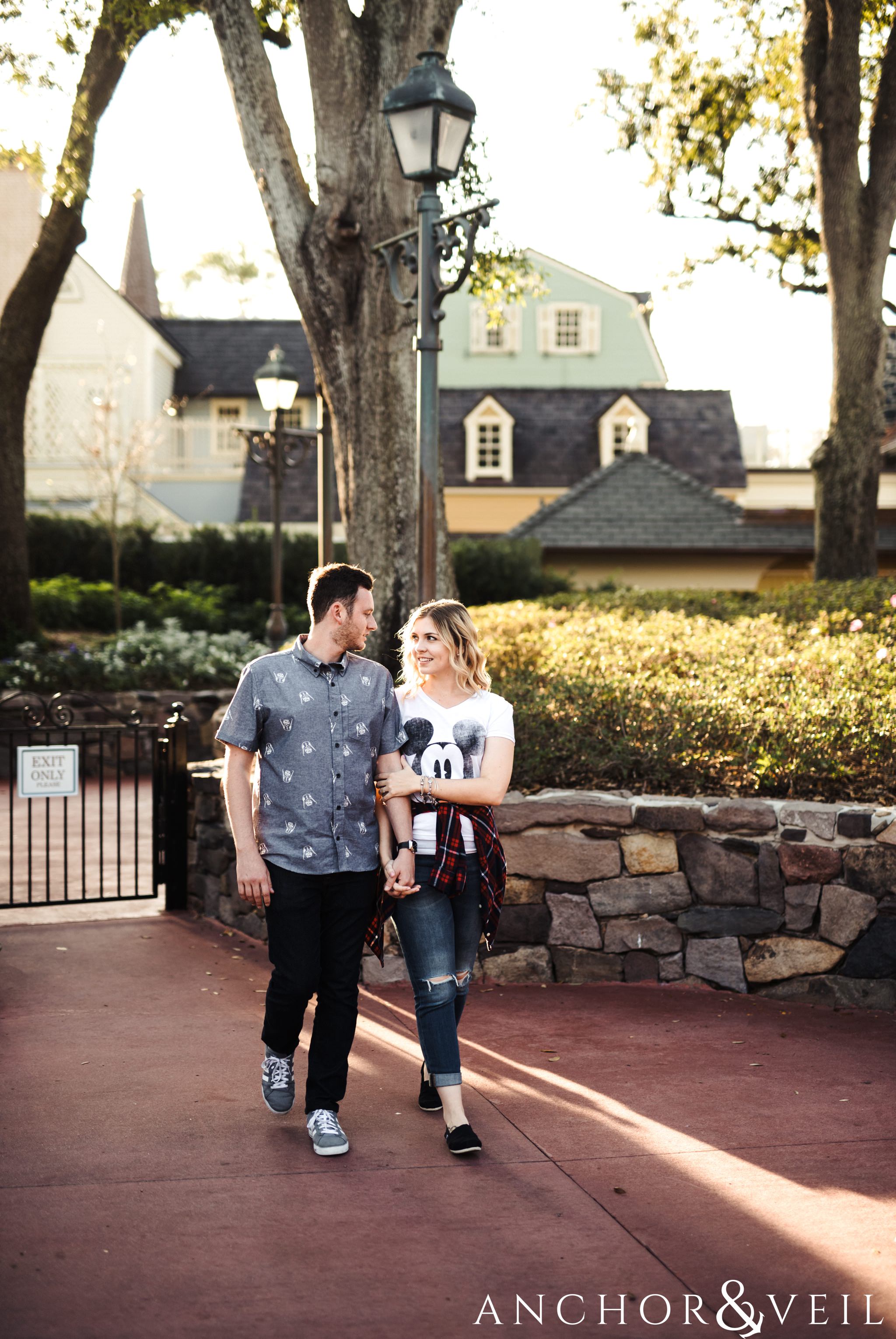 walking hand in hand during their Disney world engagement session at Disney's Magic Kingdom
