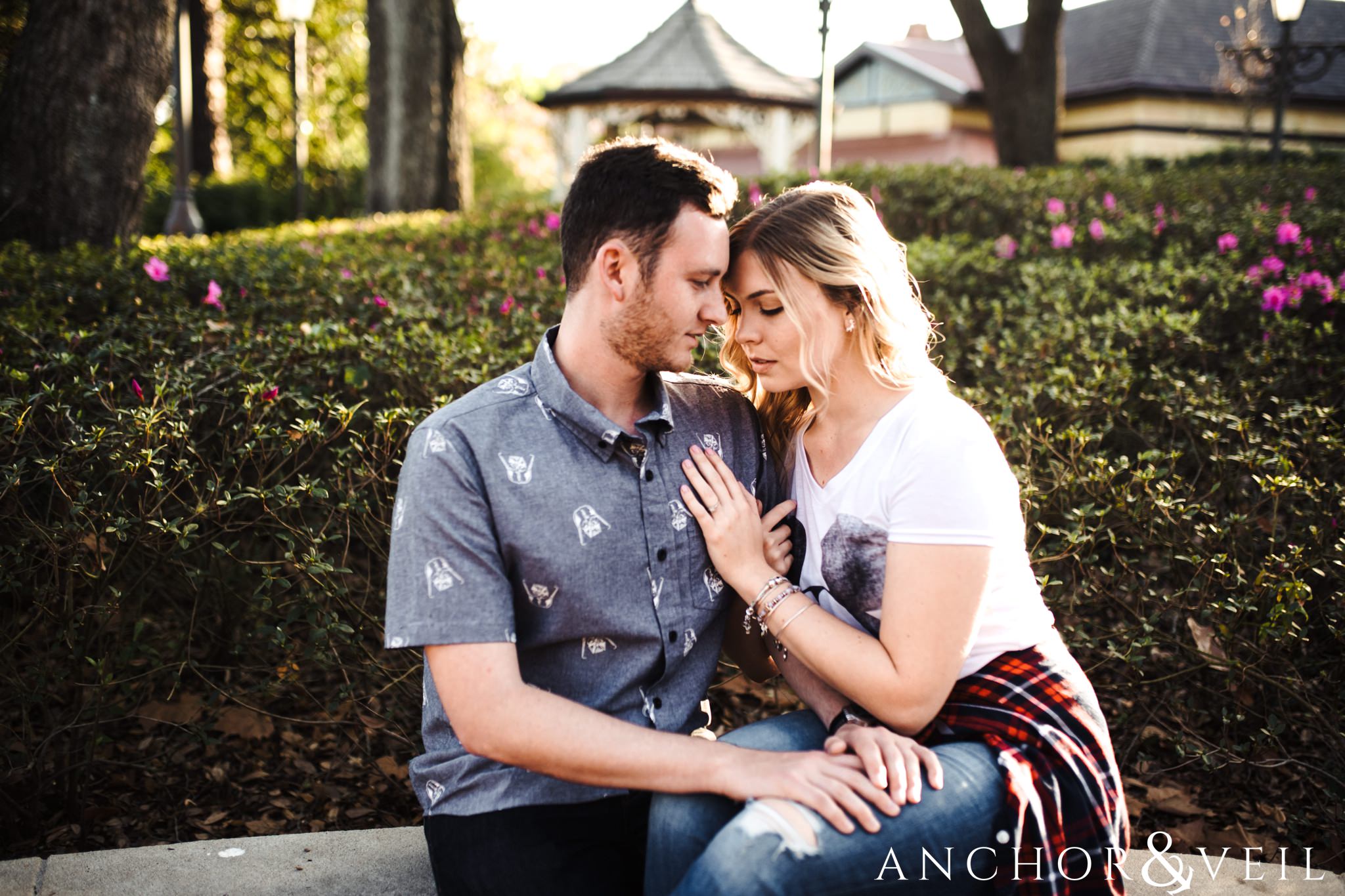 cuddling on the wall together during their Disney world engagement session at Disney's Magic Kingdom