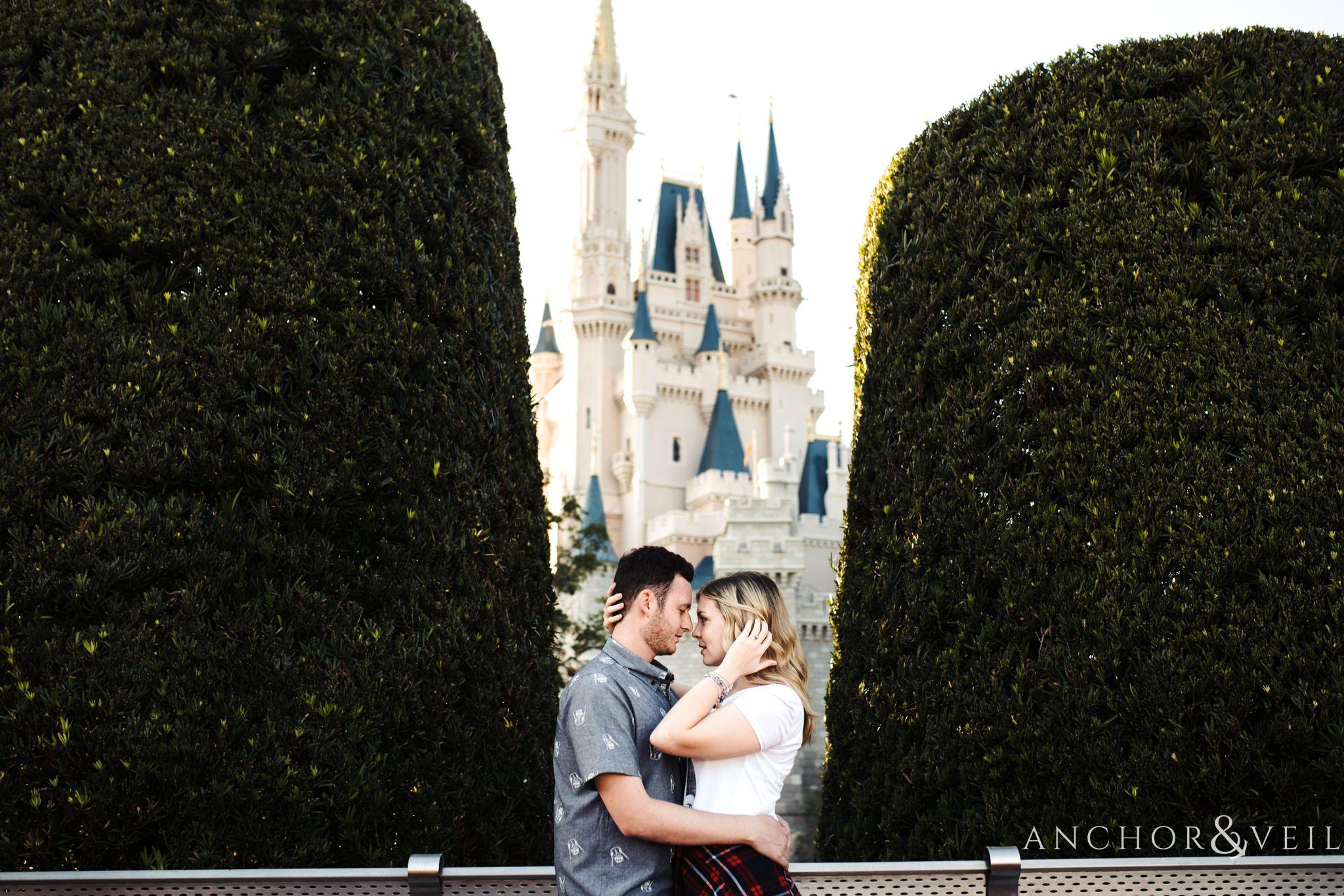 moving her hair in between the trees with the castle during their Disney world engagement session at Disney's Magic Kingdom