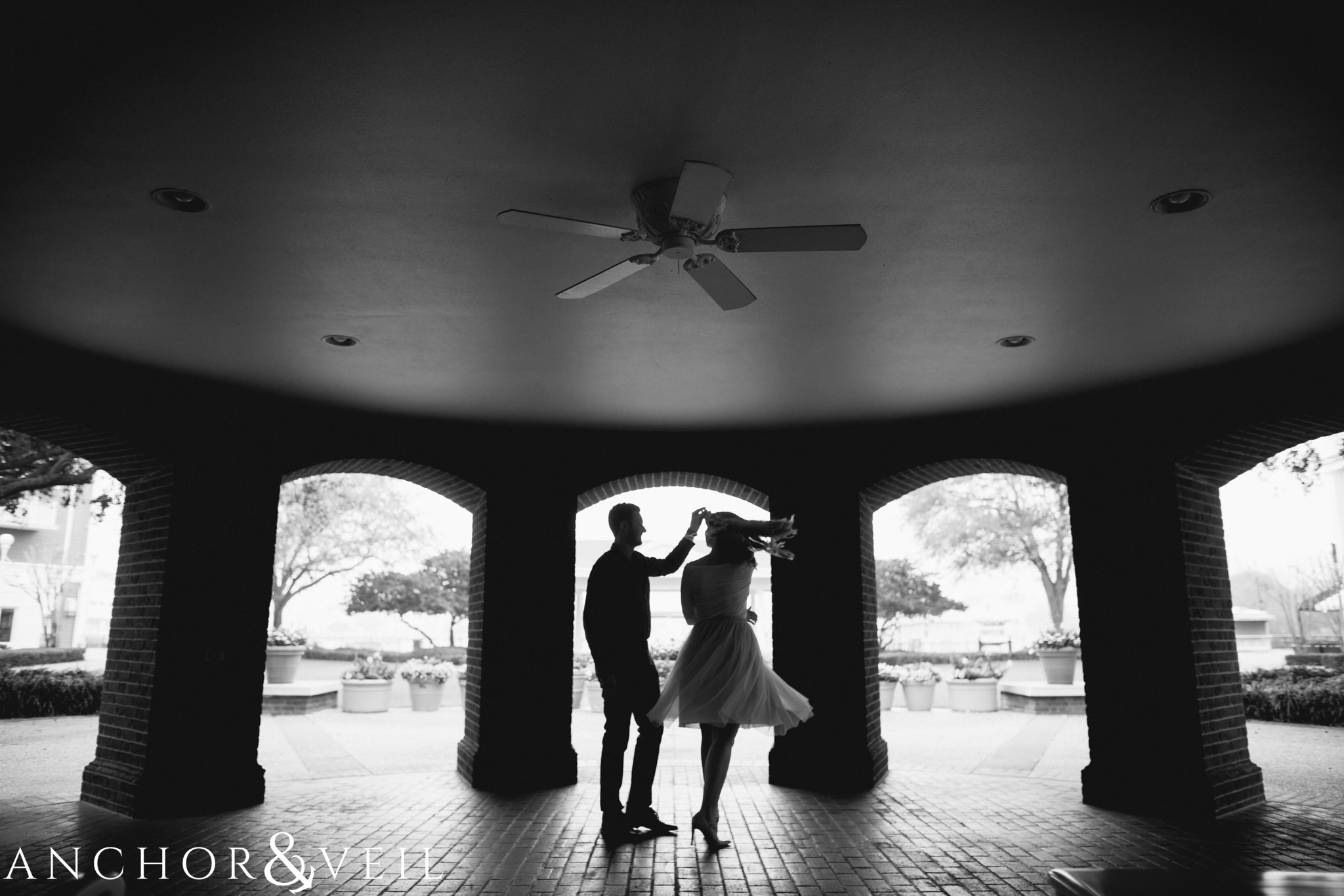 twirling her in the arches during their Disney world engagement session at the Boardwalk Hotel Inn