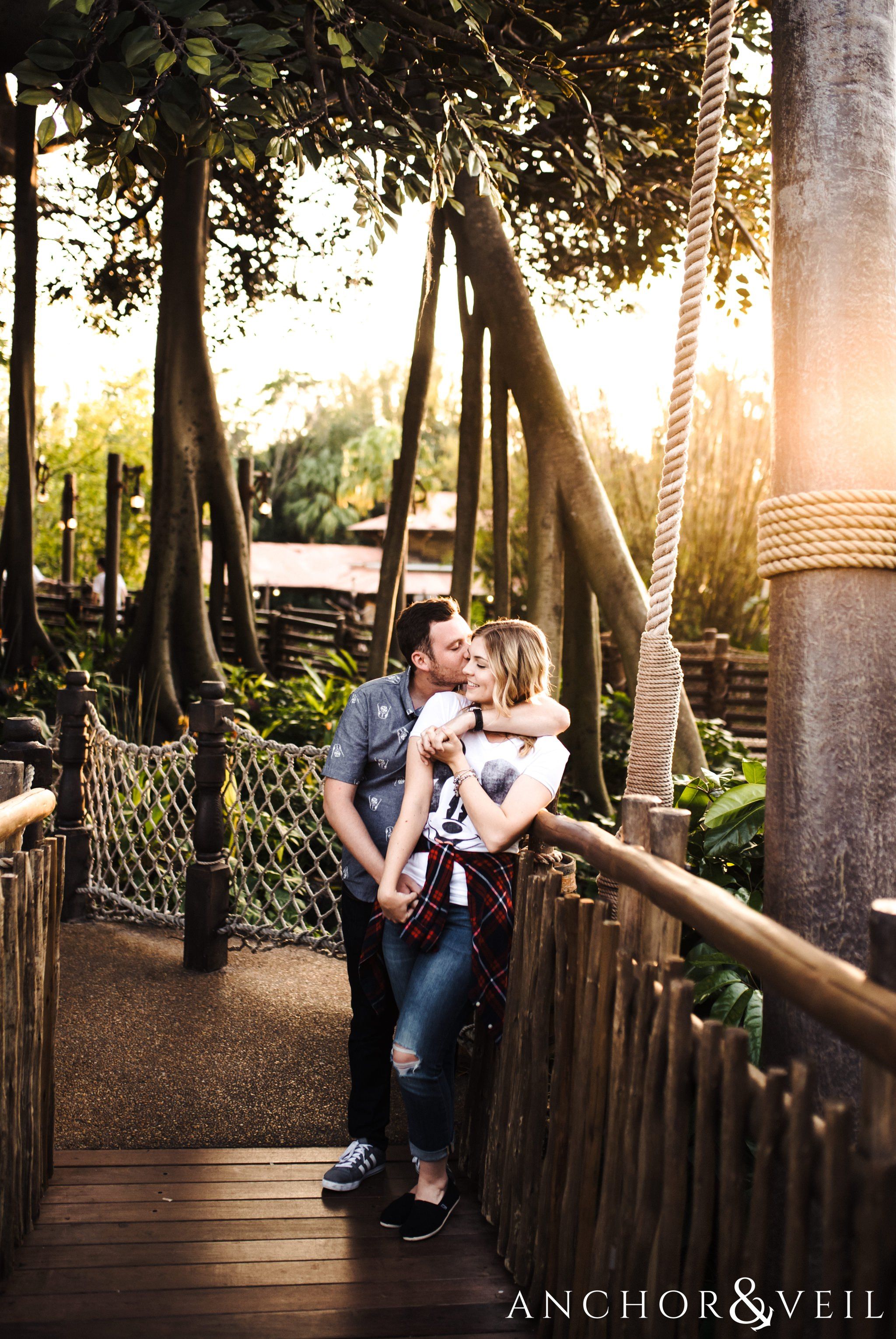 in front of Robinson Crusoe tree house during their Disney world engagement session at Disney's Magic Kingdom