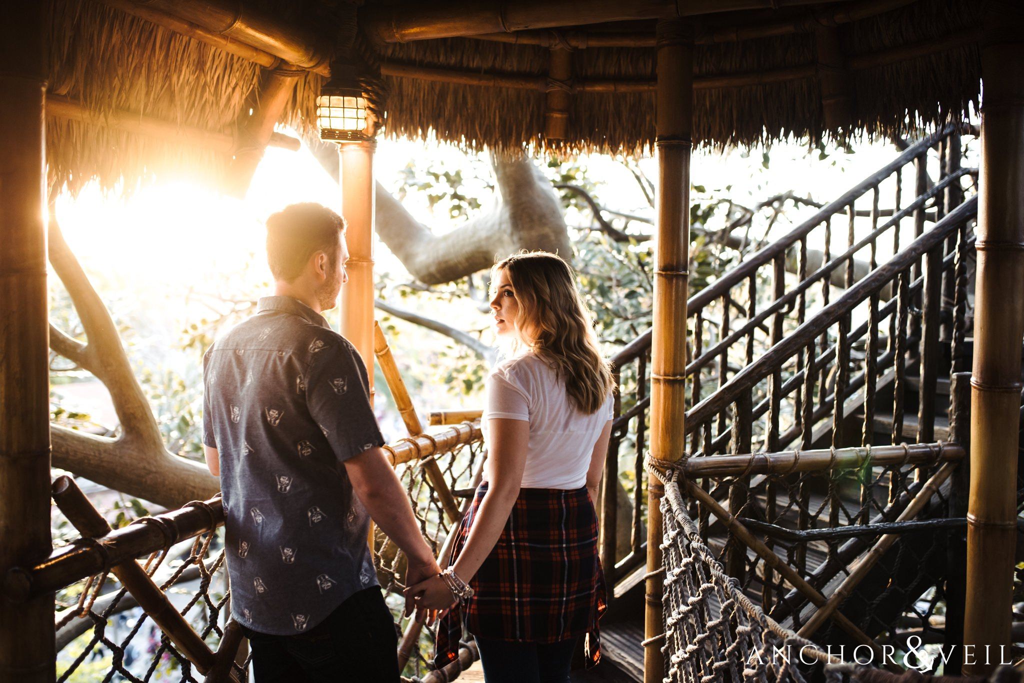 leading him up the robinson crusoe tree house during their Disney world engagement session at Disney's Magic Kingdom