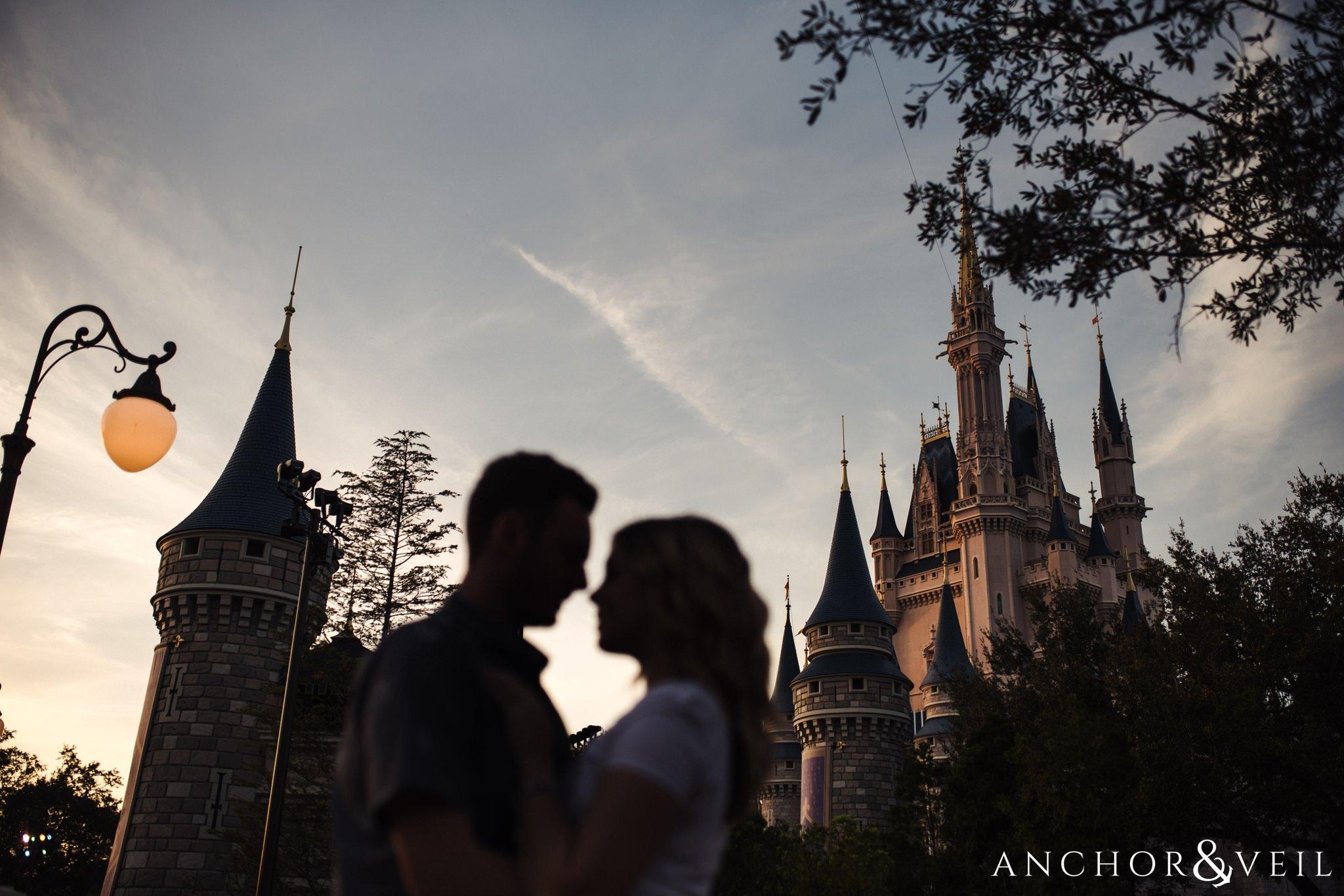 silhouette in front of Cinderella's castle during their Disney world engagement session at Disney's Magic Kingdom
