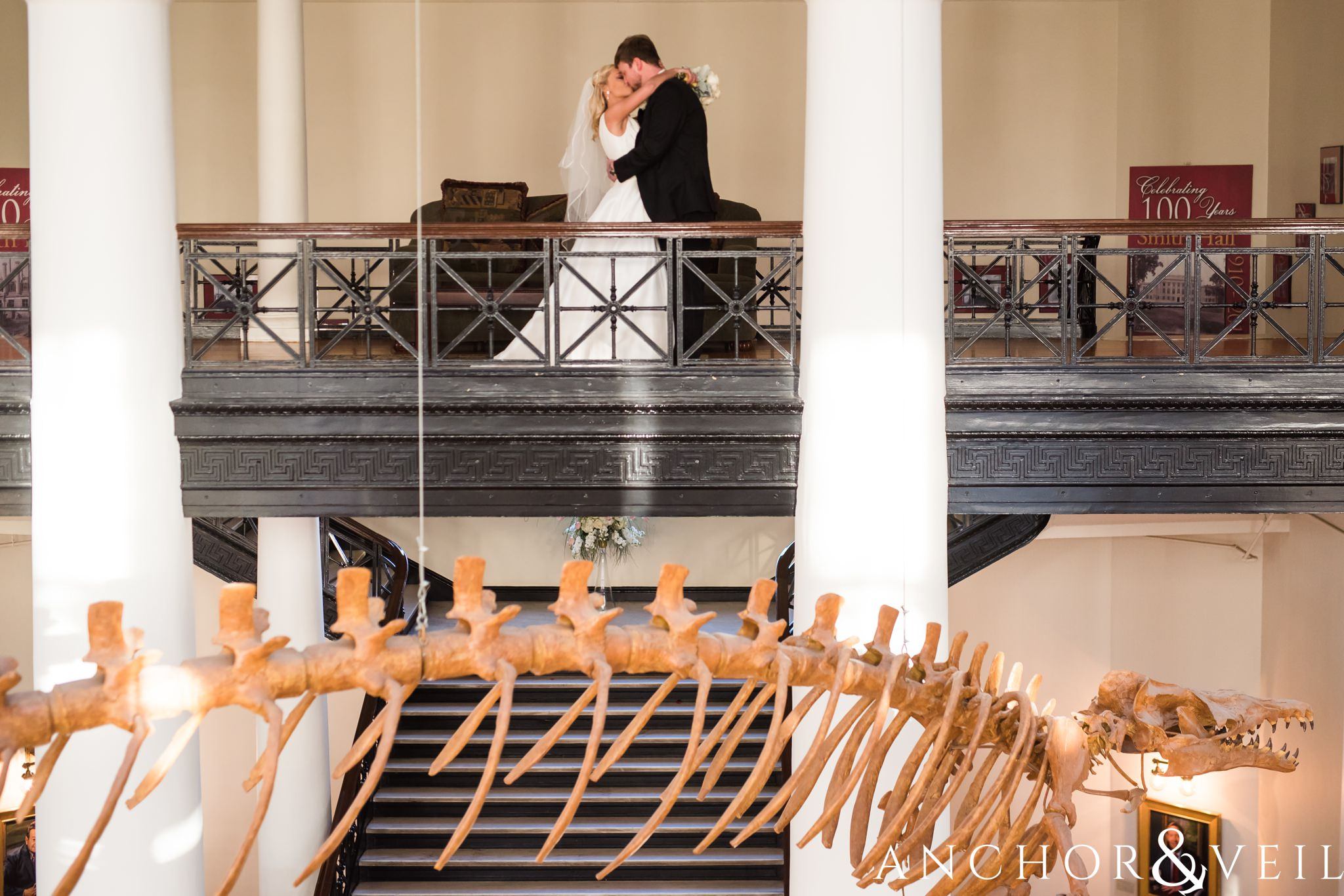 standing over the dinosaur during their Alabama Museum of Natural History Wedding
