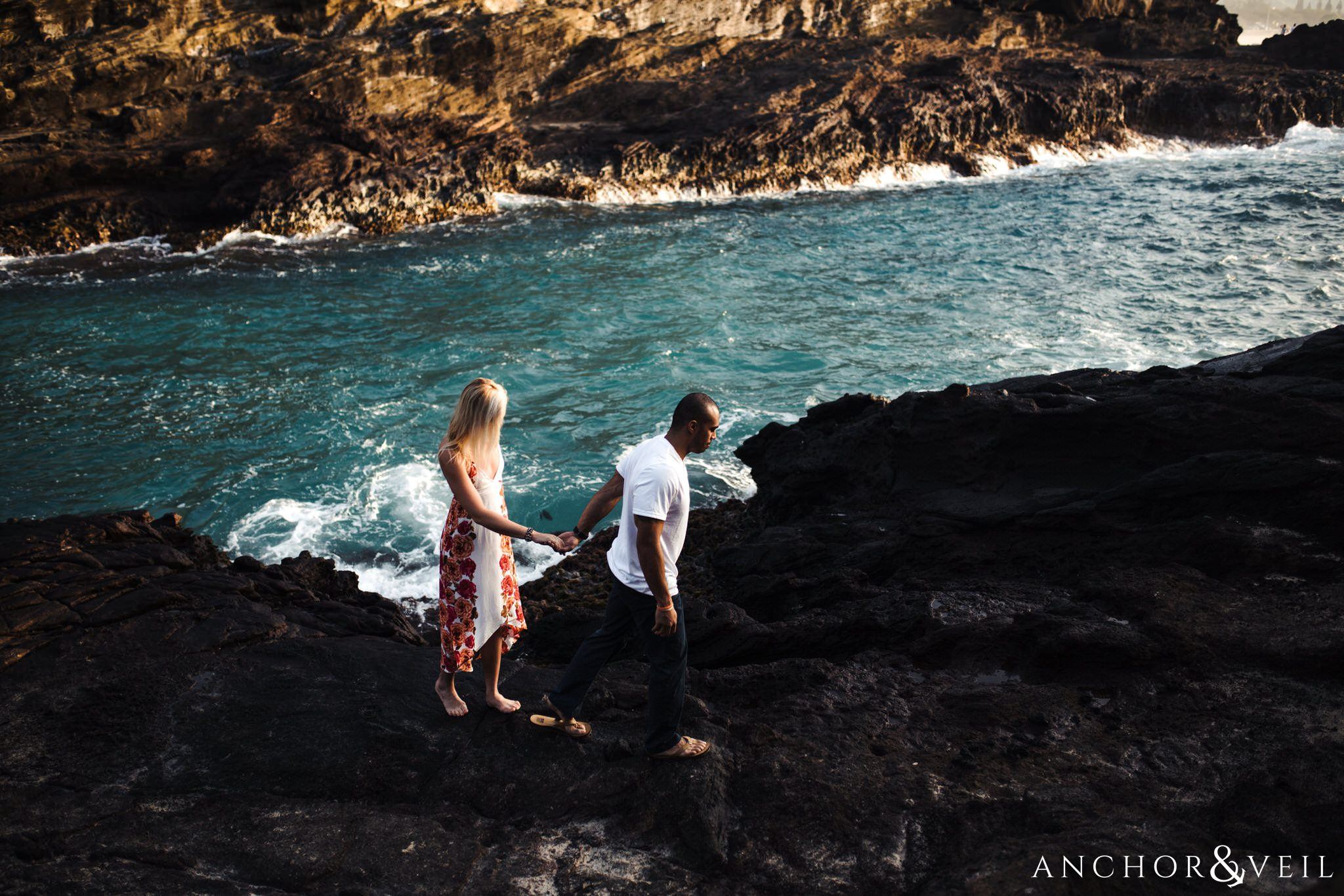walking hand in hand during their Eternity Beach Session in Honolulu Hawaii Halona Cove