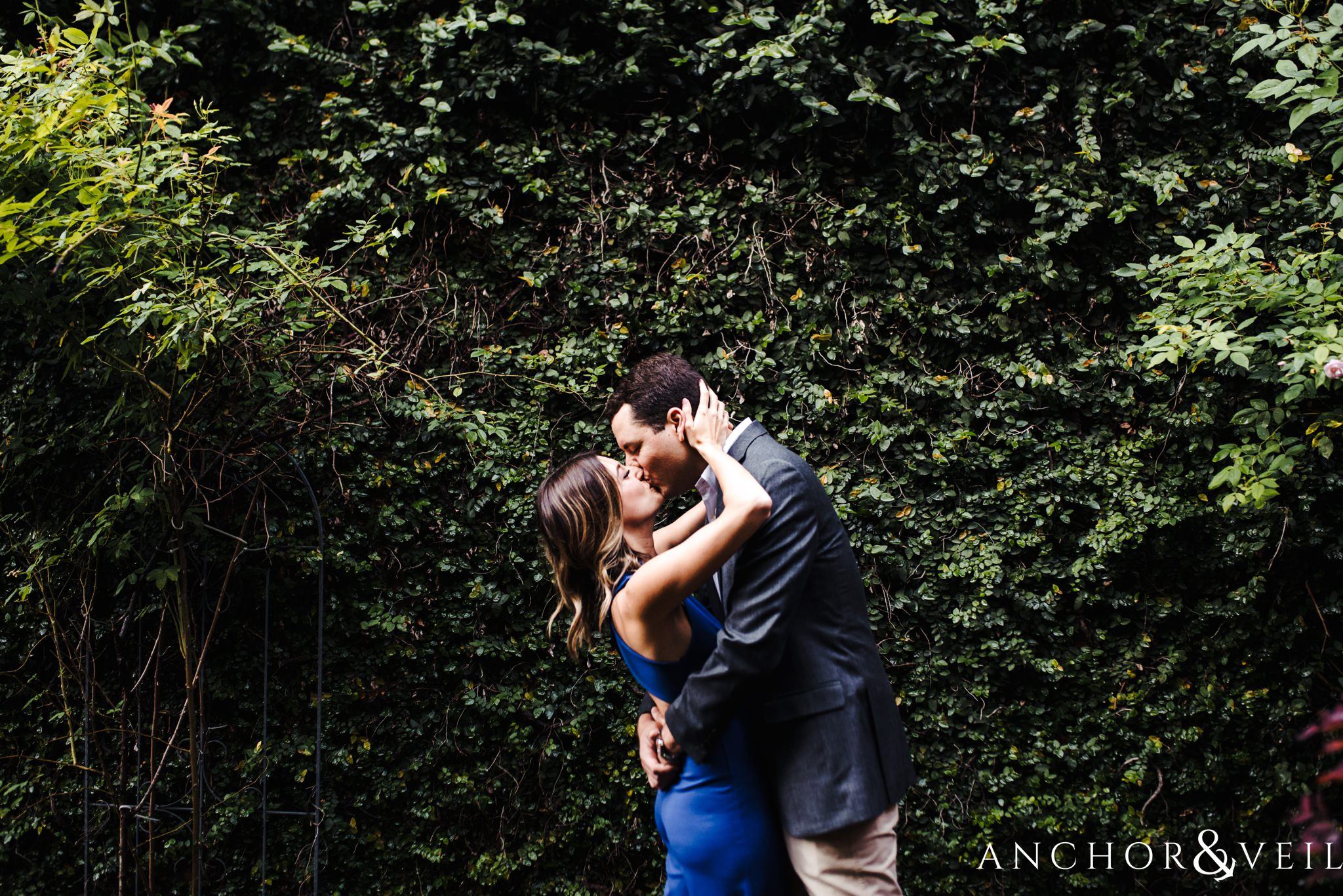 kissing in the vines during the Uptown Charlotte Sycamore Brewery Engagement Session