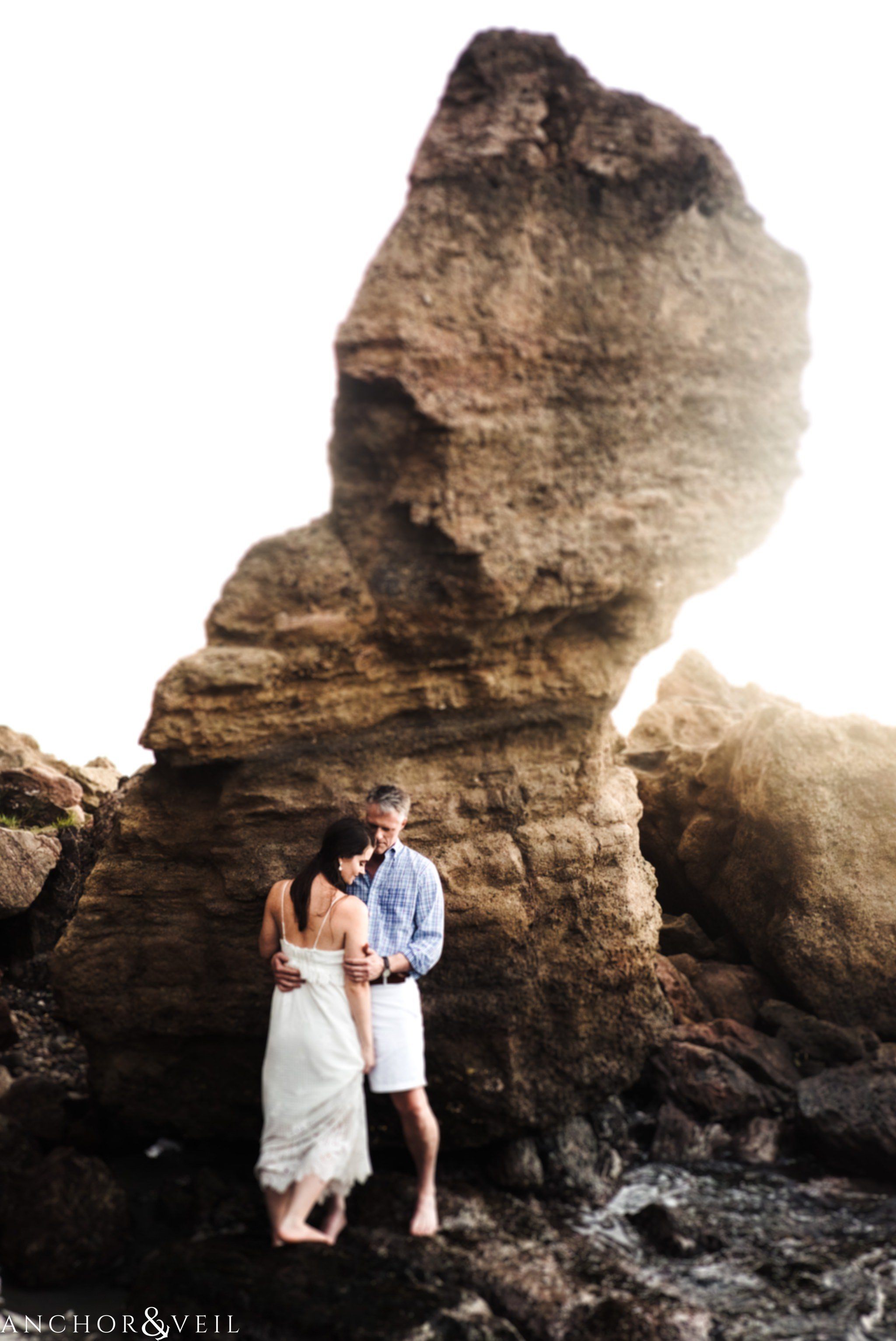 Standing on front of the large rock as they kiss and hold each other