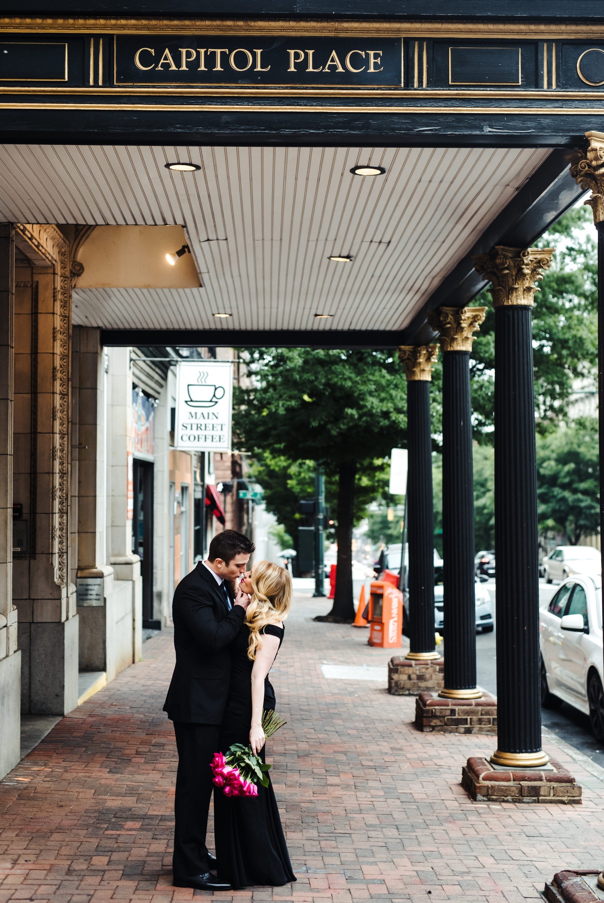 An intimate kiss under the Capitol Place sign during their Downtown Richmond Engagement Session