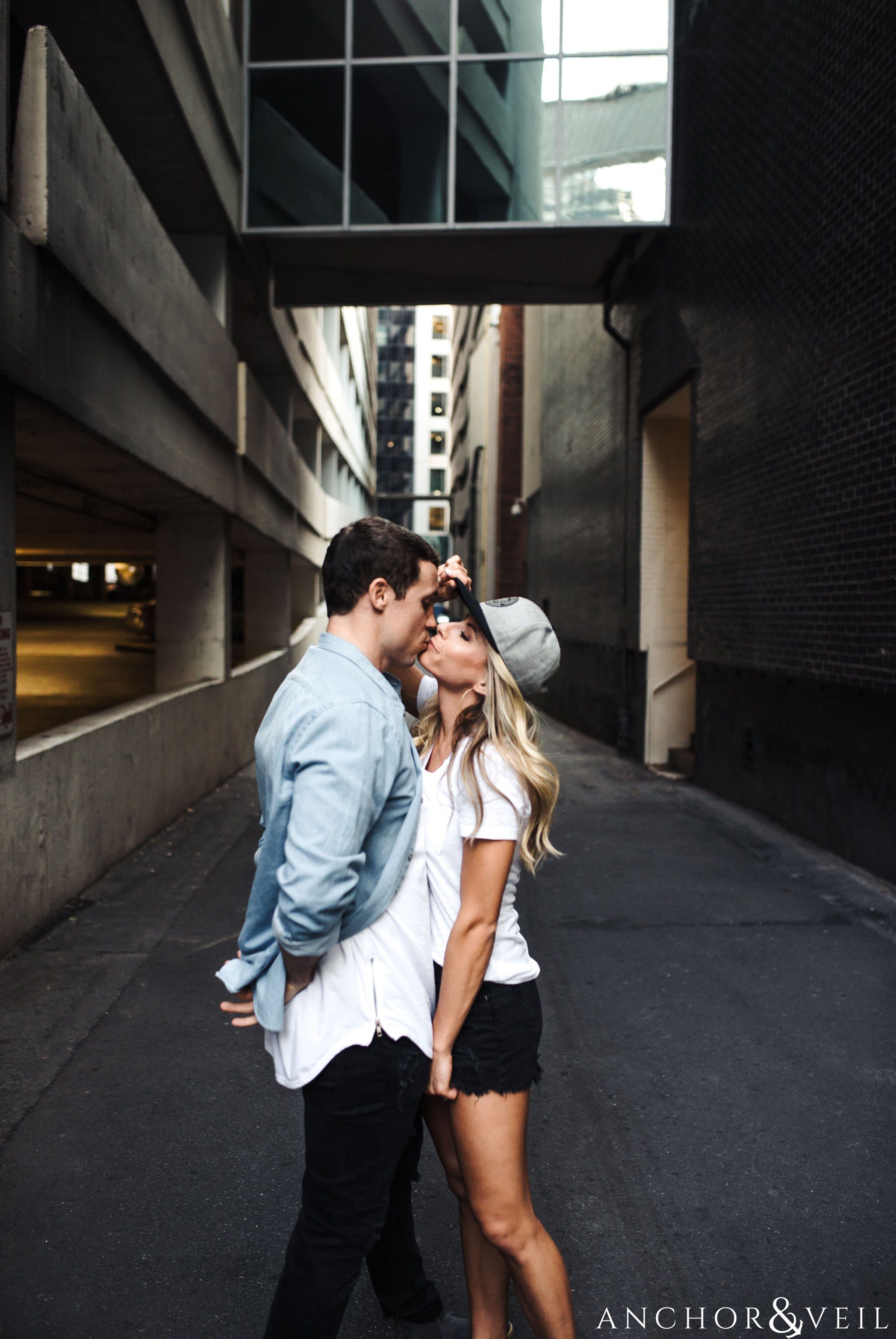 wearing his hat and kissing in the alley uptown Charlotte engagement session