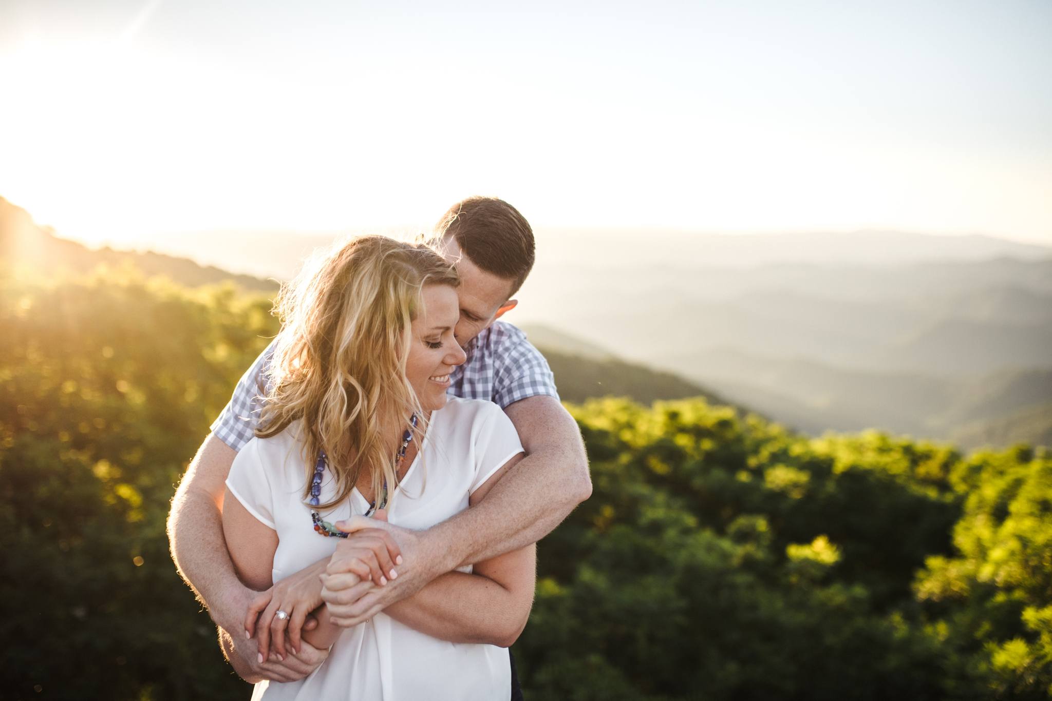a couple's sweet embrace at sunset with a mountainous view during their Craggy Gardens Engagement Session