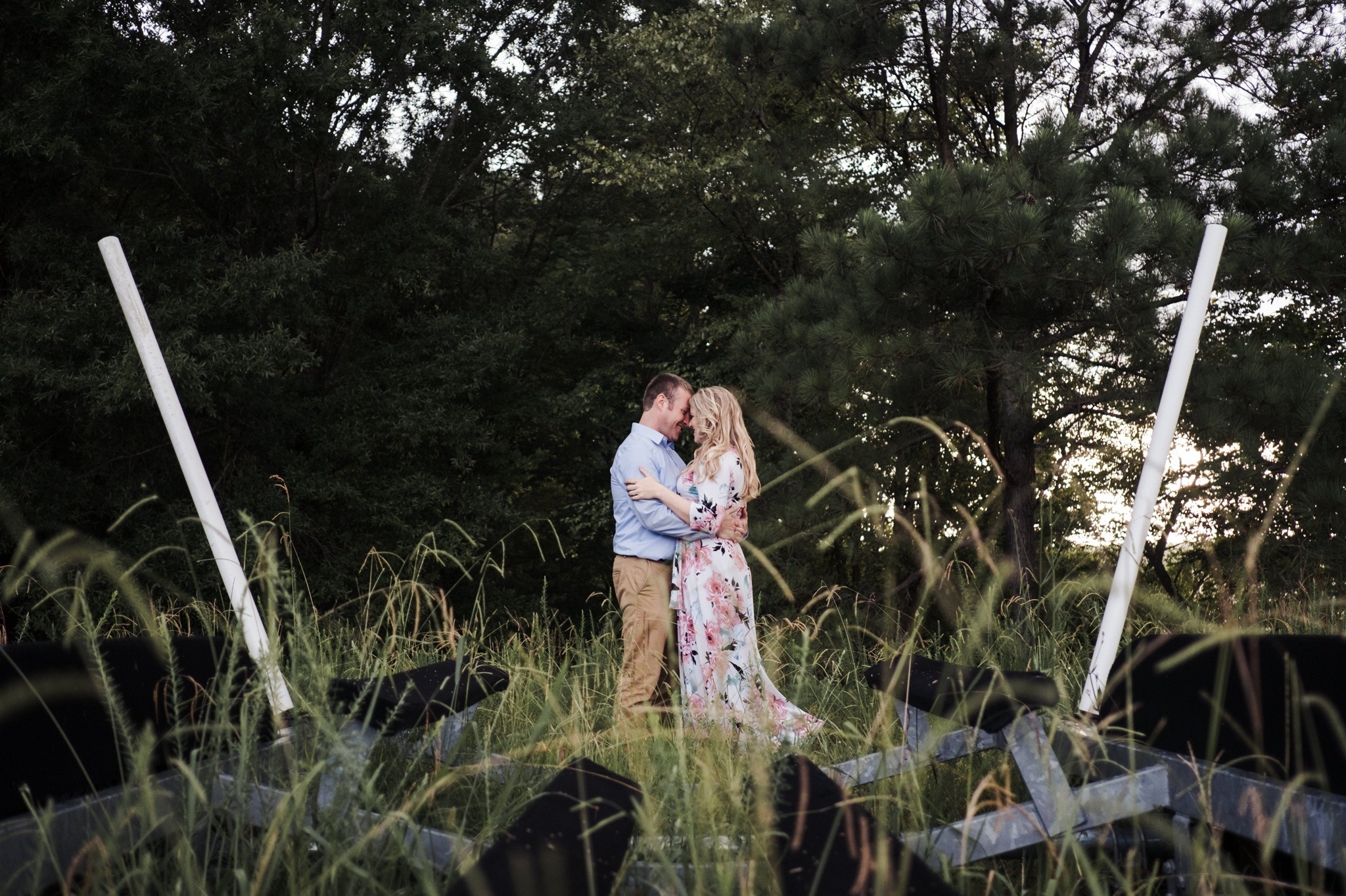 These love birds embrace all the while grass grows wild around them during their Downtown Apex Engagement Session