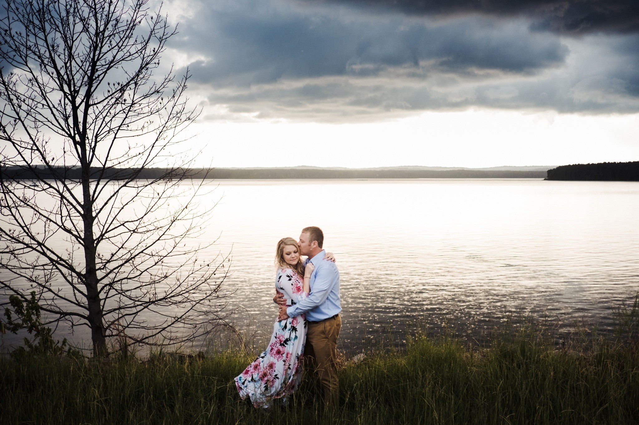 the sweet embrace from this couple on a cloudy day with a lake view during their Downtown Apex Engagement Session