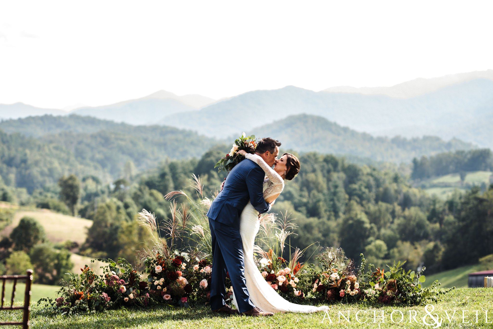kissing with the mountains in the background during her The Venue Wedding in Asheville