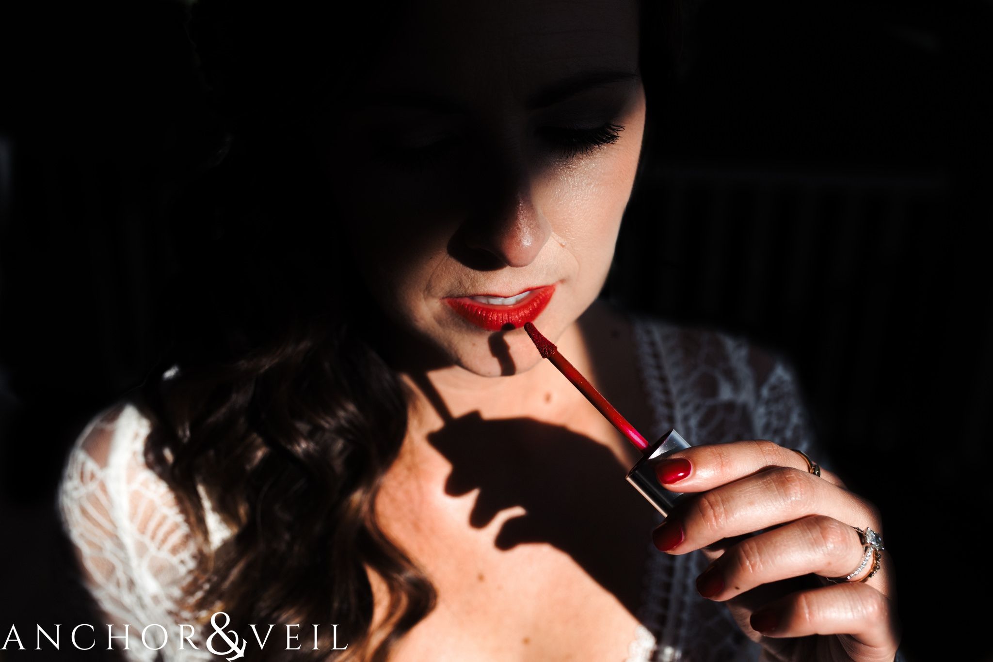 putting on red lipstick with shadows during her The Venue Wedding in Asheville