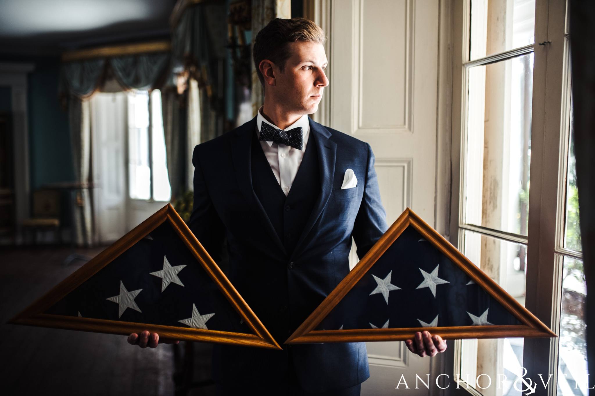 Groom with grandfather's marine flag during their William Aiken house Wedding in Charleston Sc