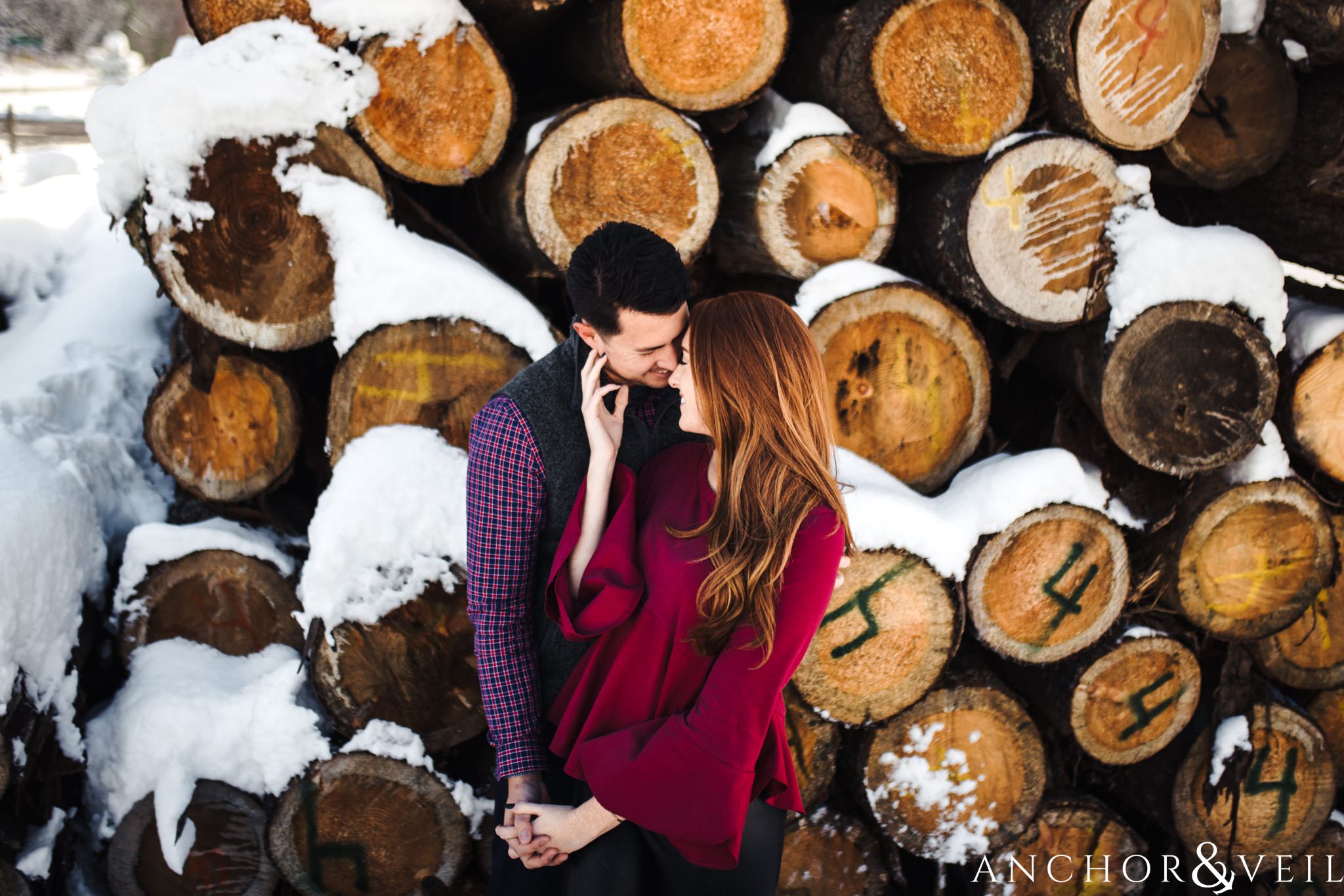bringing him close next to the logs during their Snowy Asheville Engagement Session
