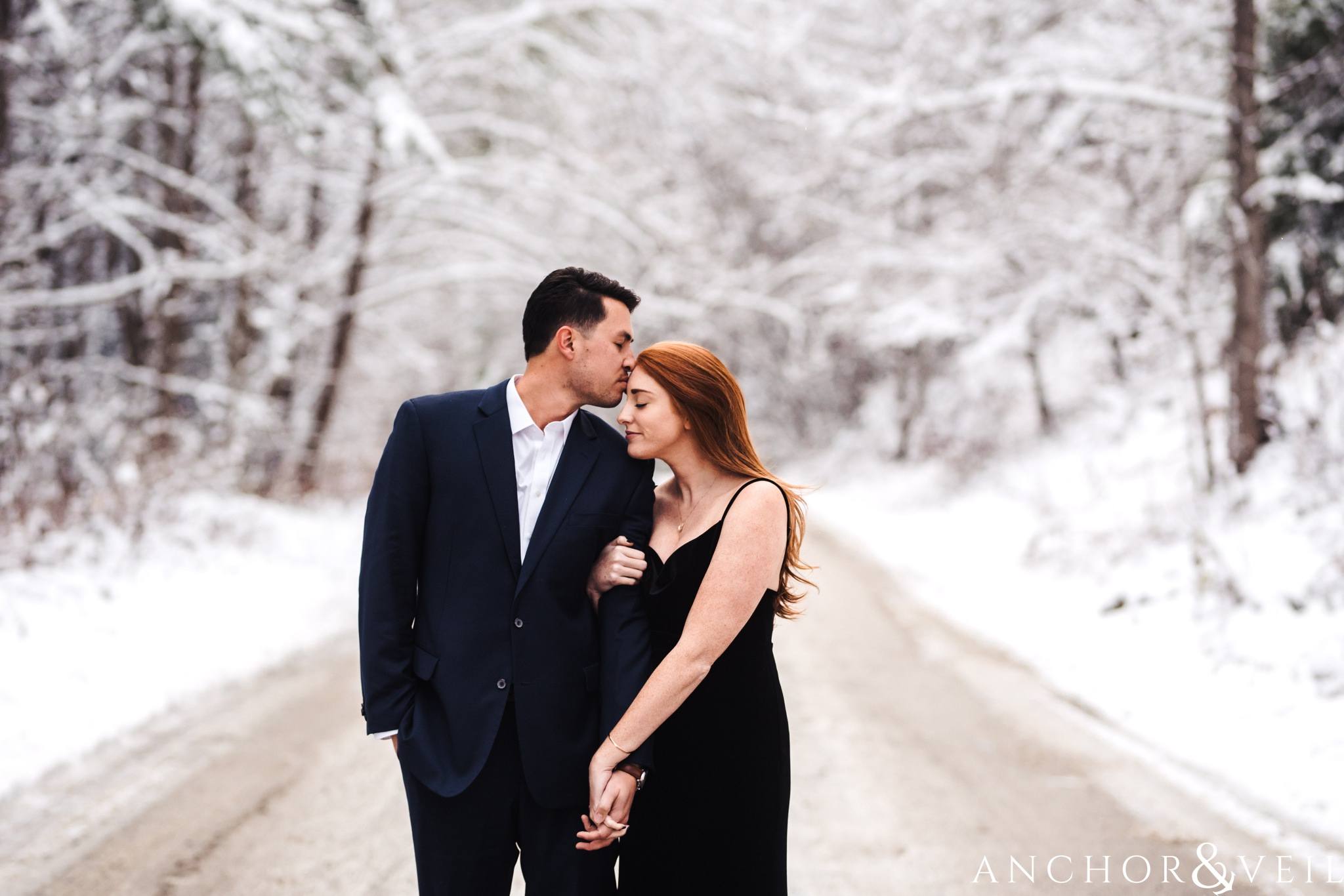 kissing her on the forehead during their Snowy Asheville Engagement Session