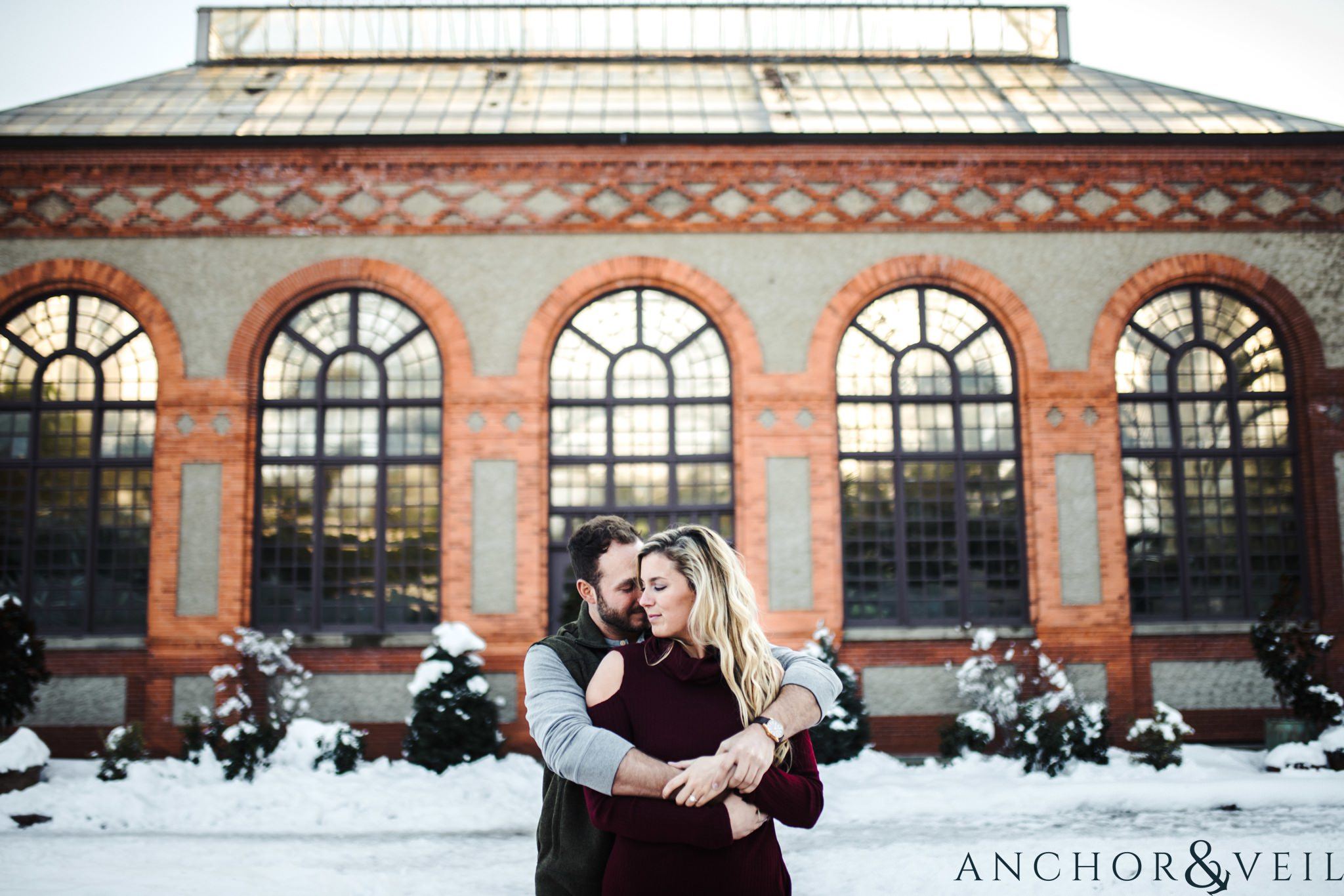 in front of the garden greenhouse during their Snowy Biltmore Engagement Session