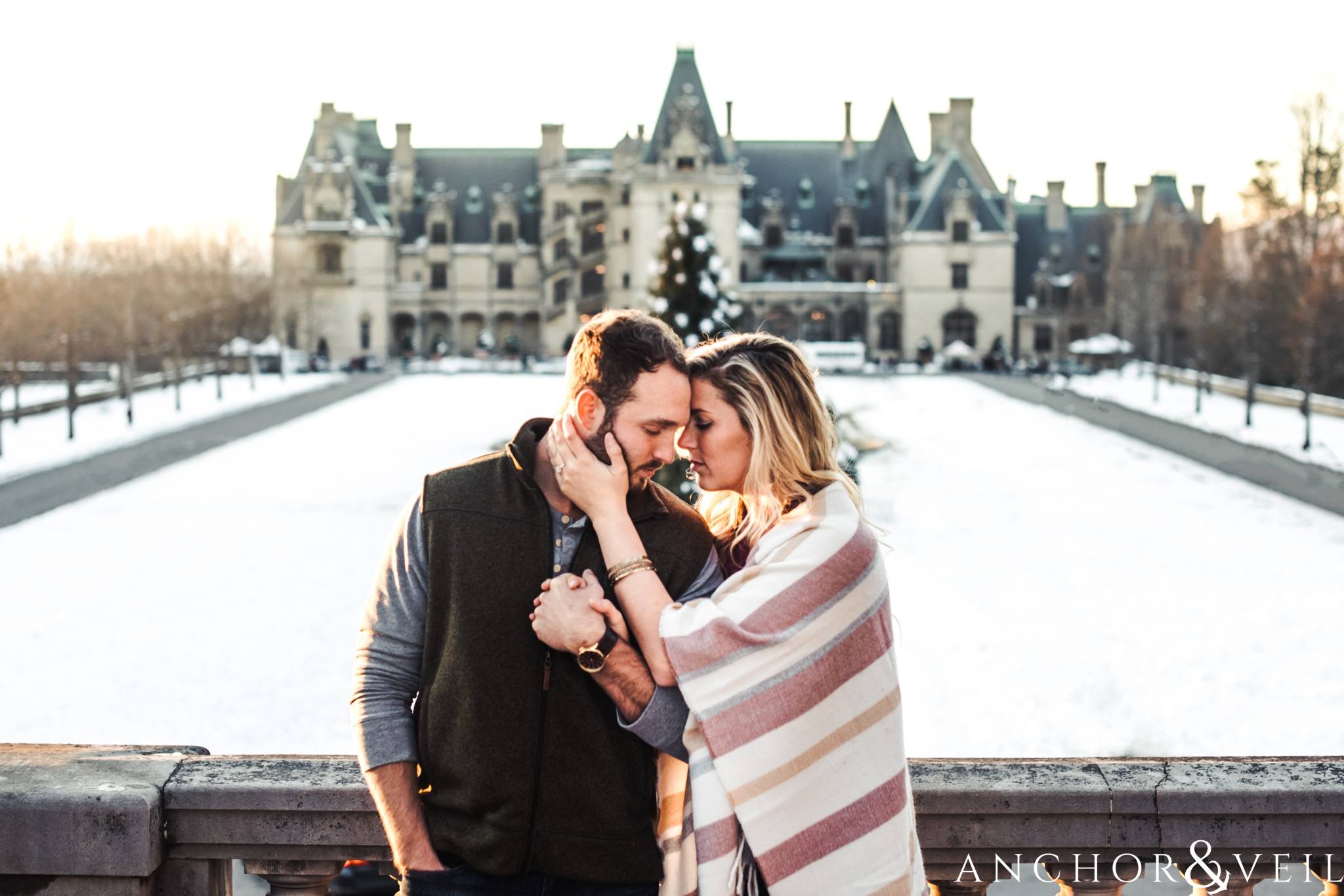 holding each other in front of the house during their Snowy Biltmore Engagement Session