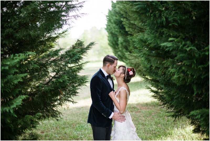Bride and groom between the trees at the NC old monroe armory wedding in monroe north carolina