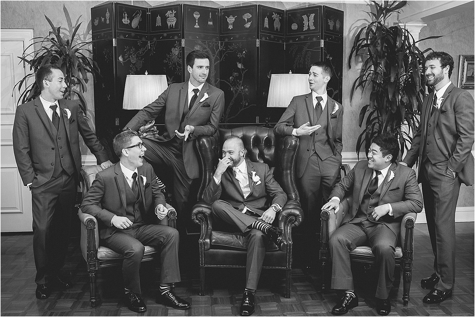 groomsmen laughing in the chairs at the Charlotte City Club wedding in charlotte North Carolina