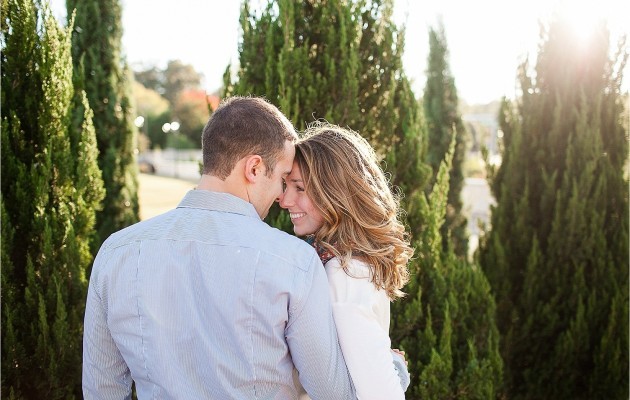 incredible sun flare light as they stand forehead to forehead during the engagement session at midtown park in charlotte north carolina