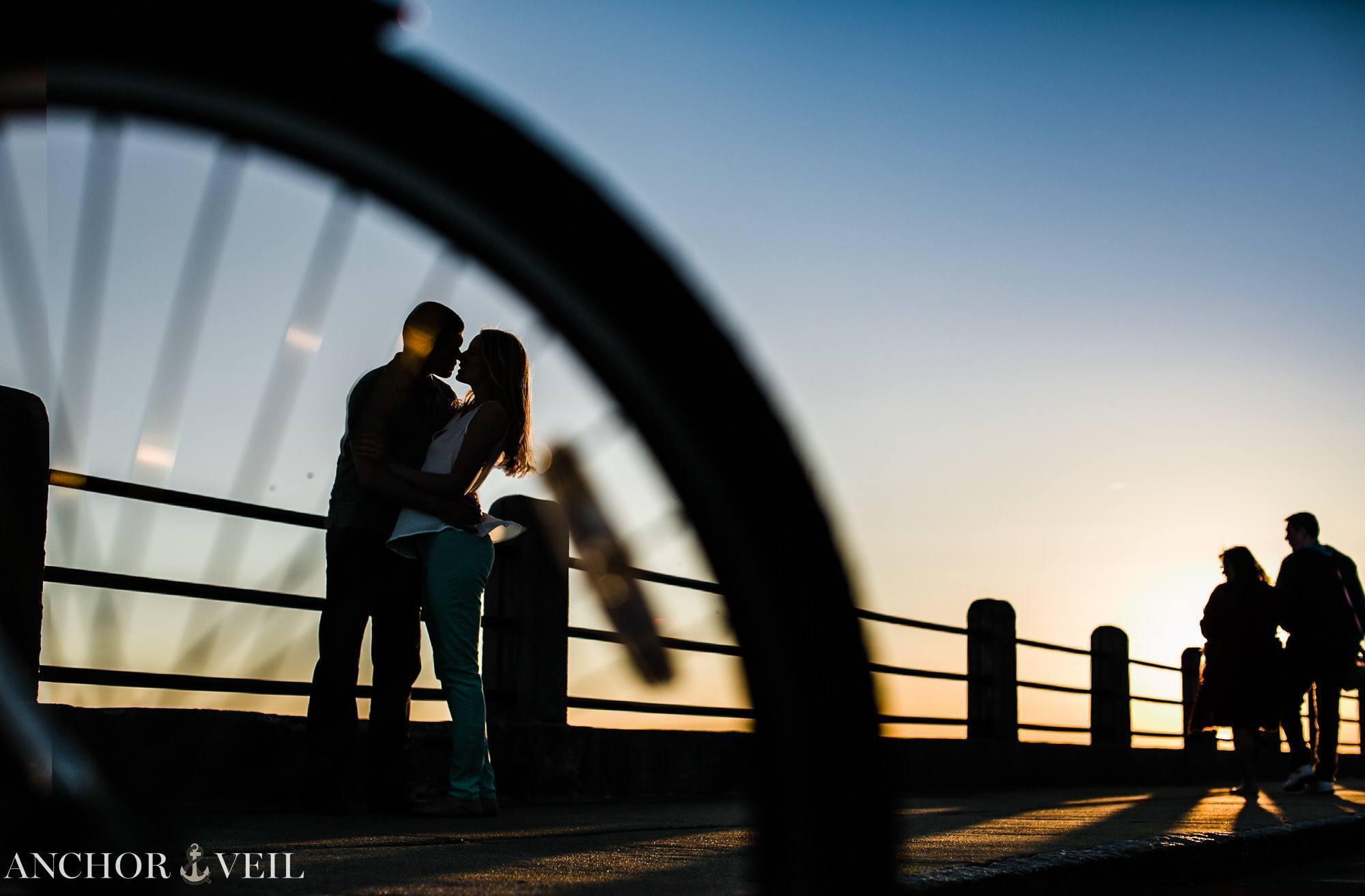 shooting the silhouette through the bike wheel while the couple kiss