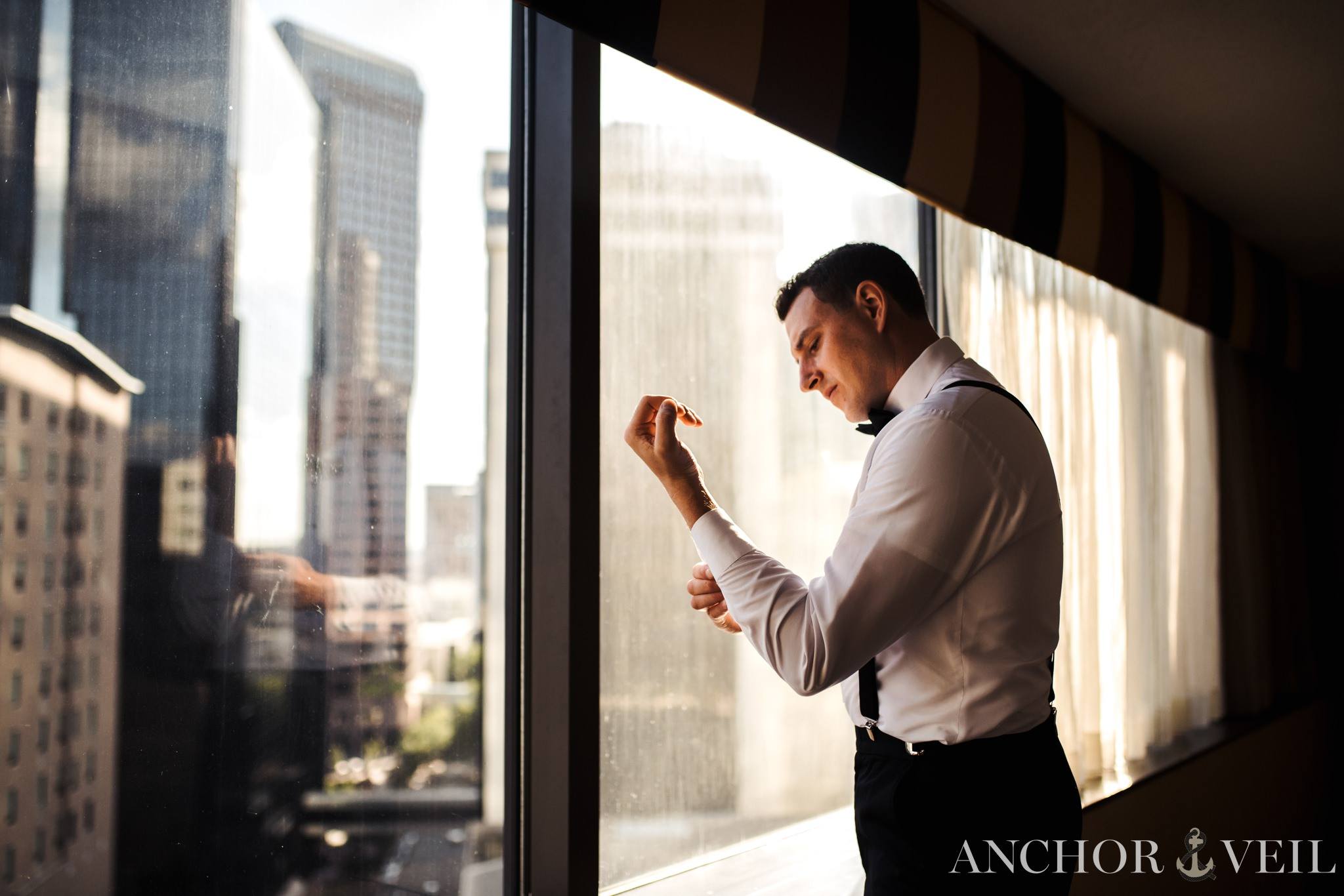 groom getting ready with the charlotte skyline in the background at the omni hotel