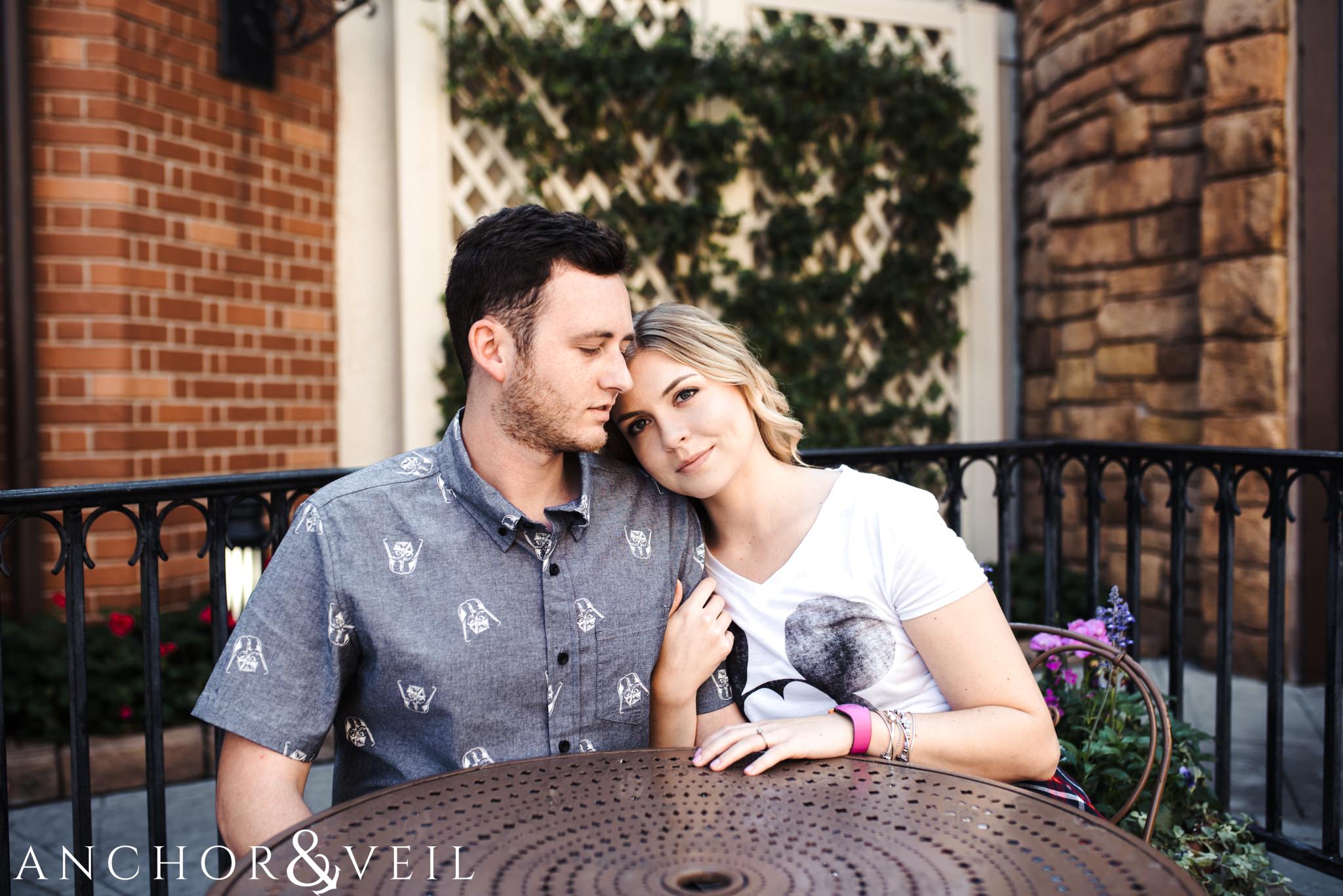 sitting at the table in france during their Disney world engagement session at Disney's Epcot