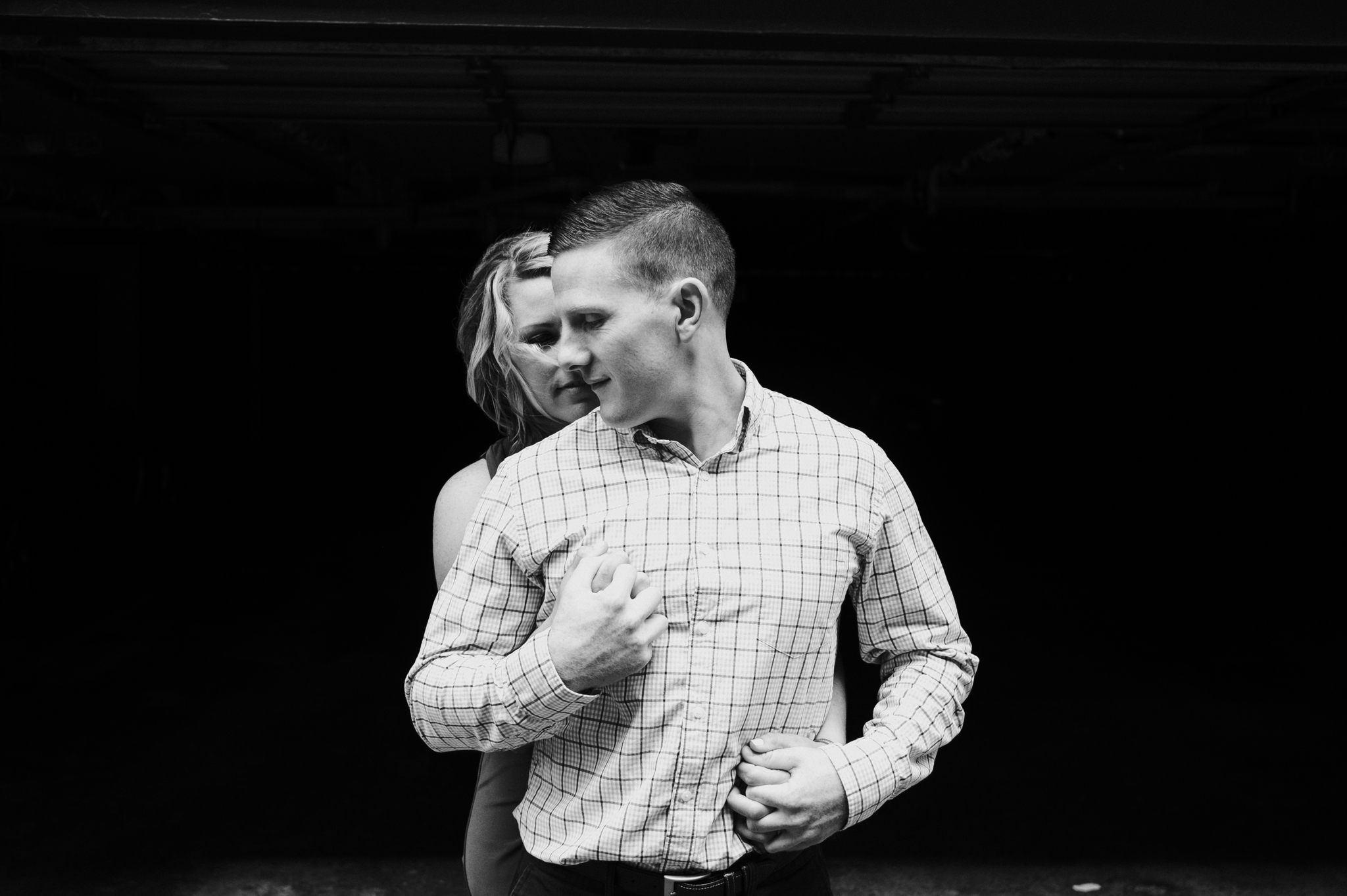 Black and white photograph of a couple holding each other in the dramatic lighting during the Craggy Gardens Engagement Session