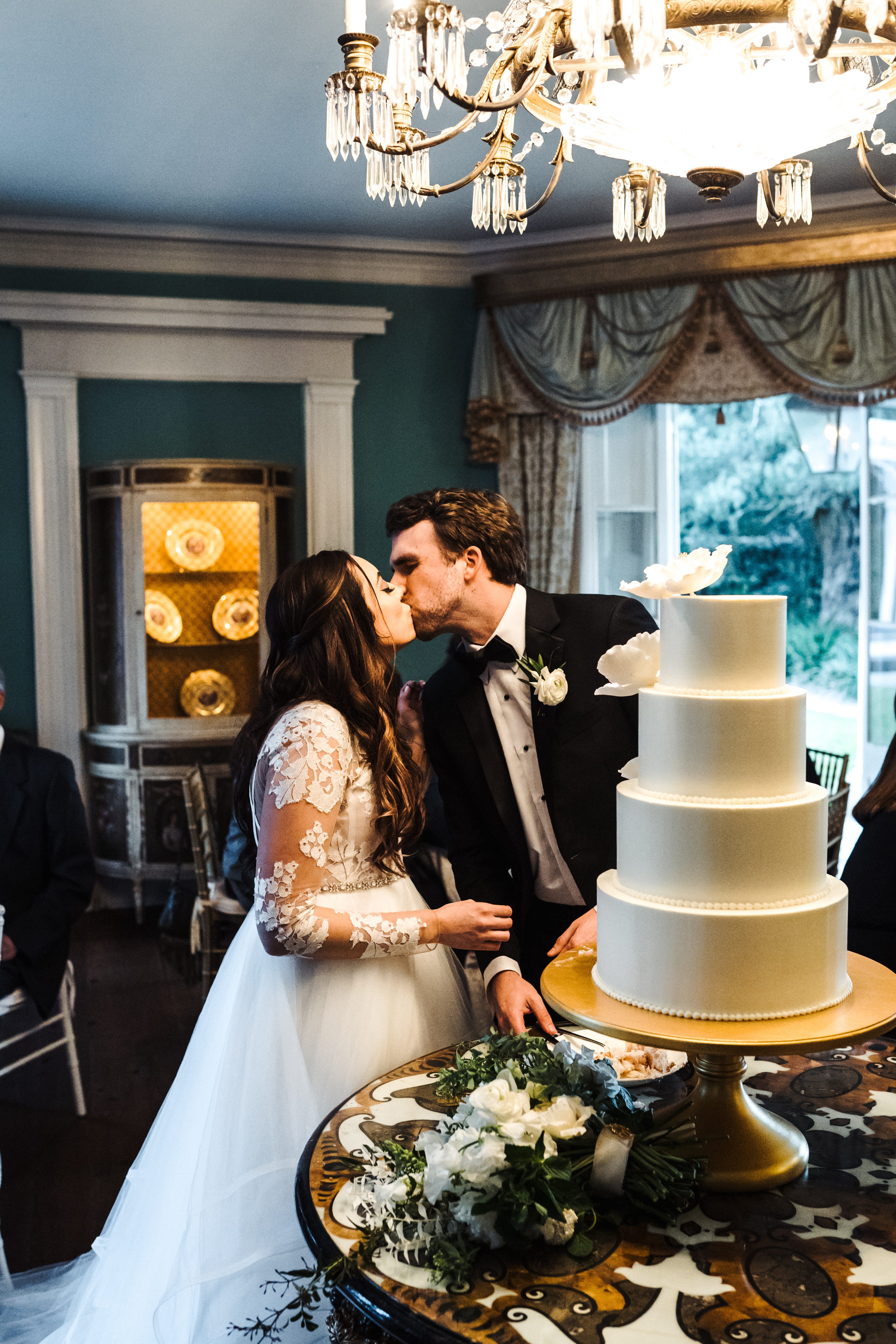 The bride and groom kiss while cutting cake at the William Aiken House Wedding