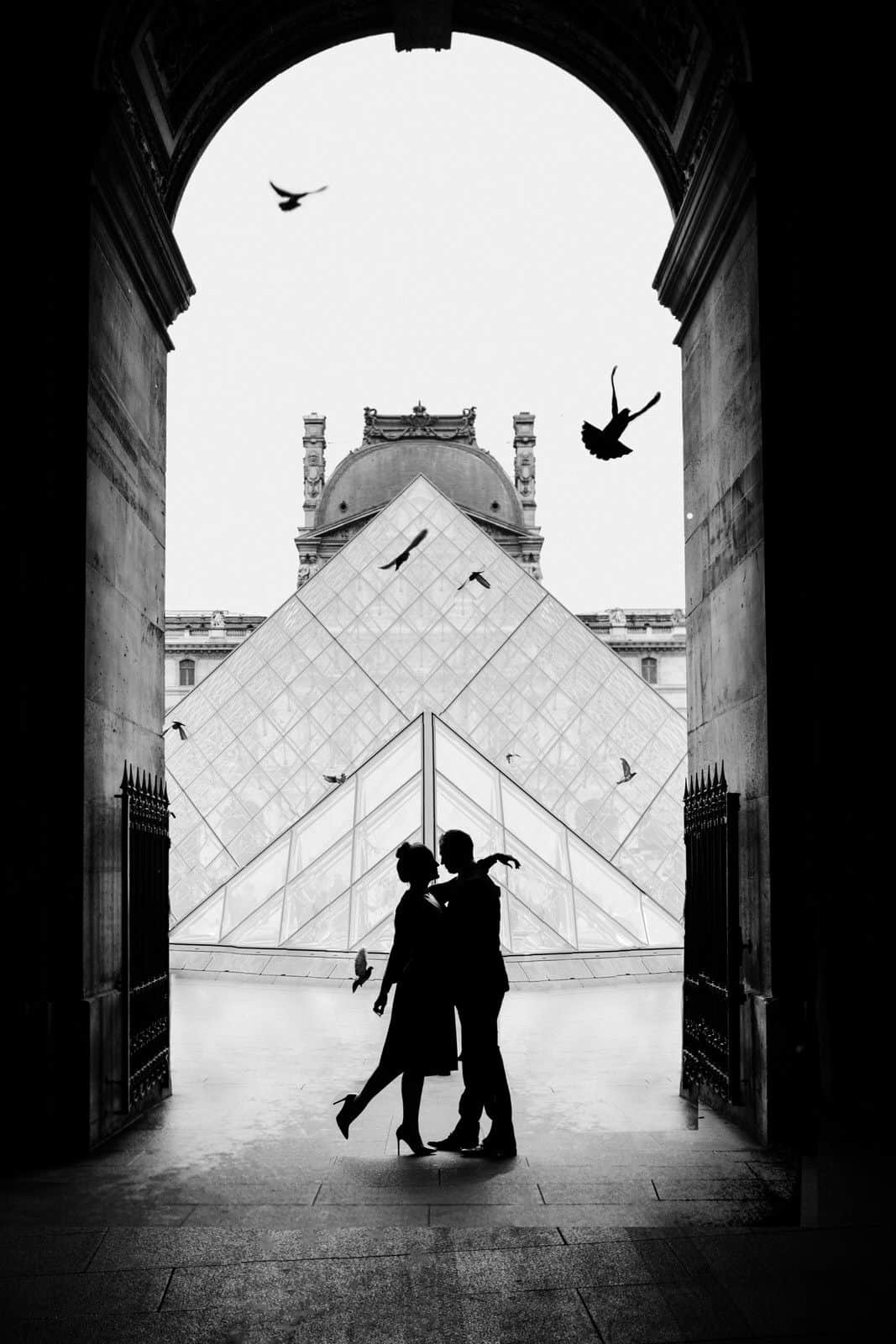 Standing together in front of the Lourve during their destination elopement in Paris