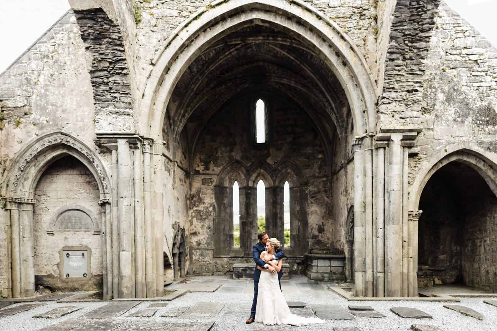 holding each other at corcomroe abbey after their Destination Wedding elopement