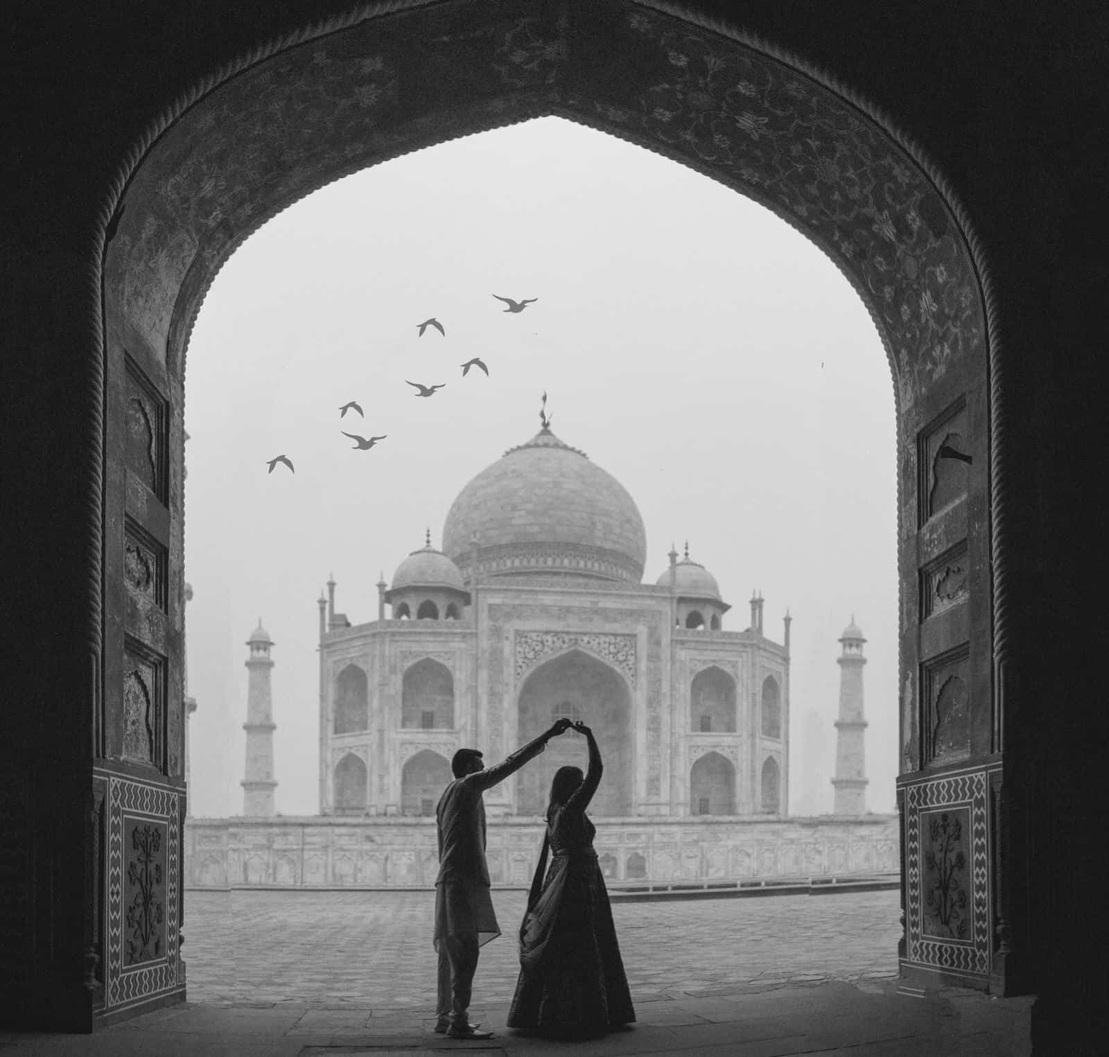 Twirling her under the arch with the Taj Mahal in the Background after their Destination Wedding